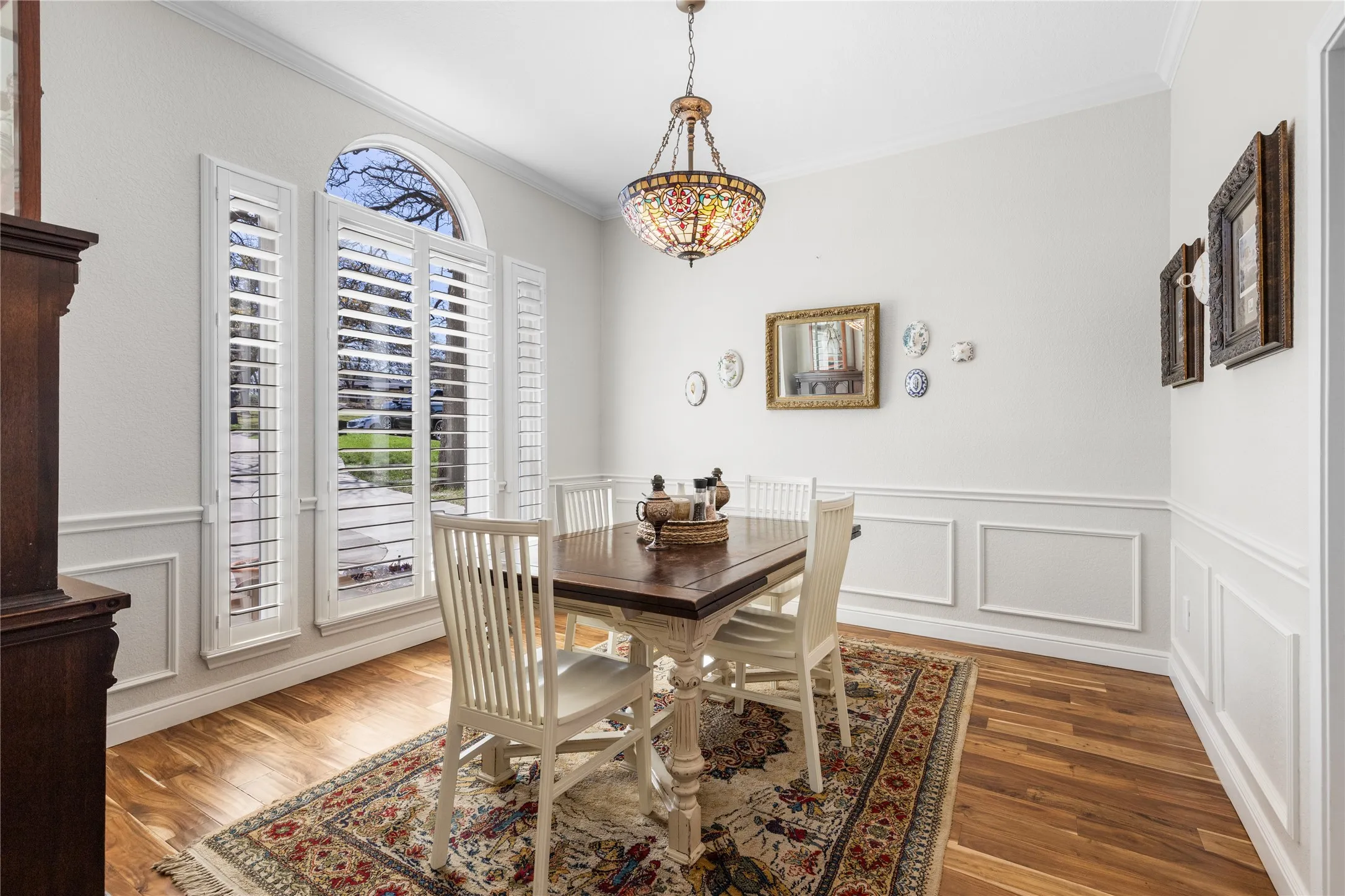 Dining space with a decorative wall, healthy amount of natural light, a wainscoted wall, crown molding, and wood finished floors