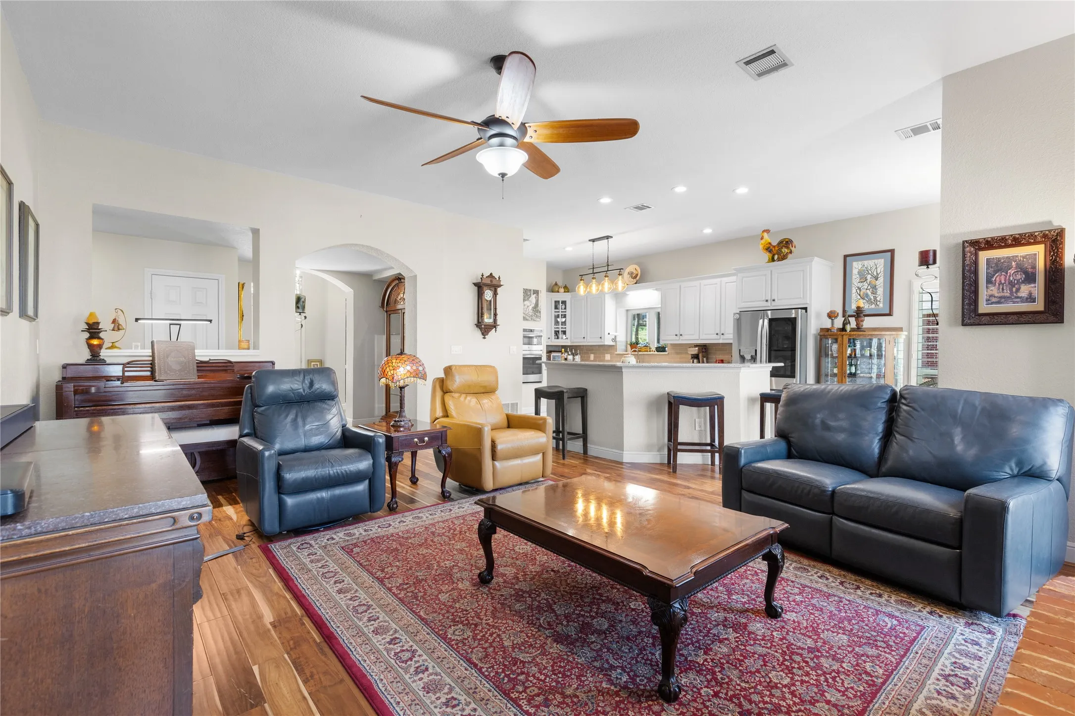 Living area with arched walkways, ceiling fan, recessed lighting, and light wood finished floors
