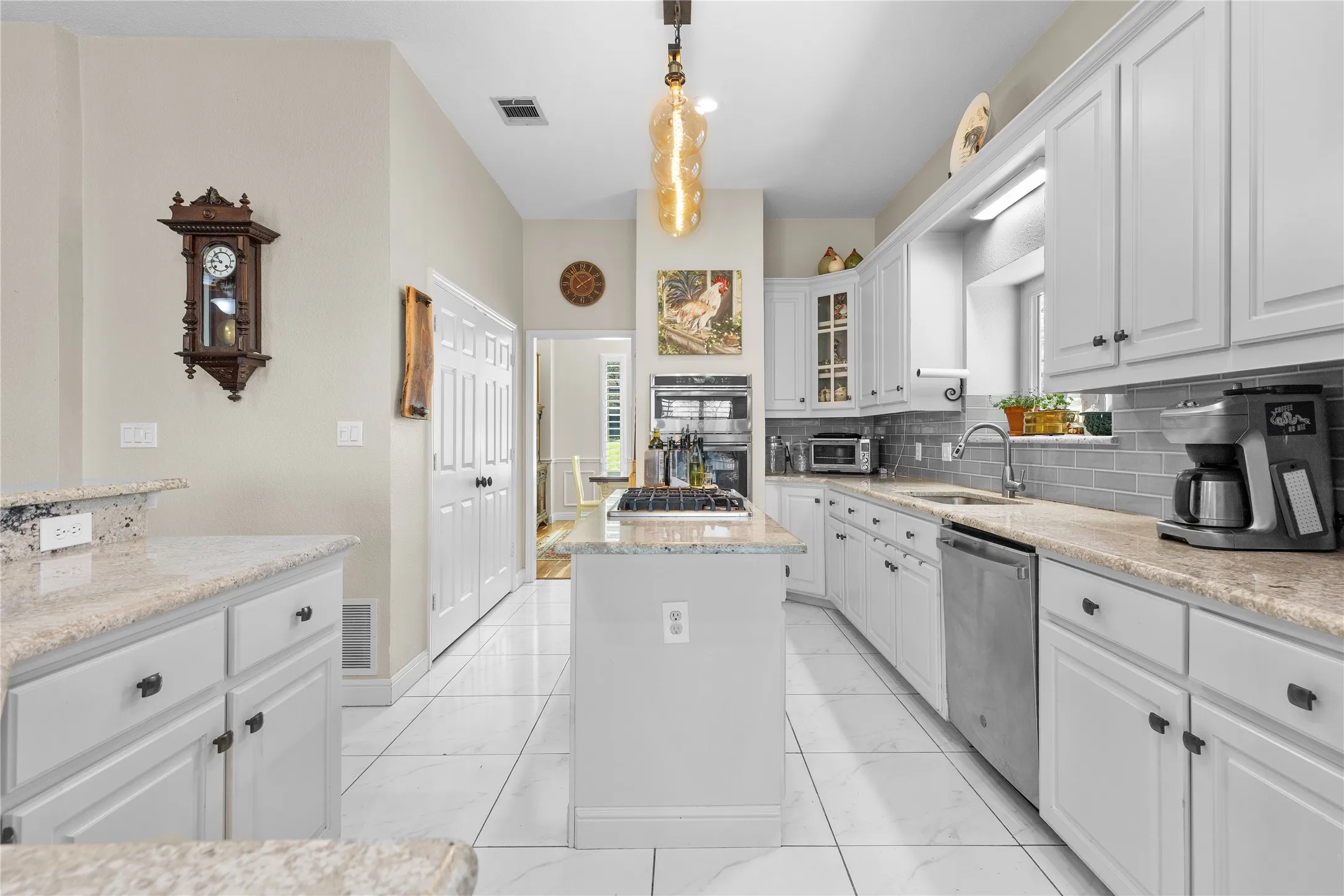 Kitchen with a center island, white cabinetry, glass insert cabinets, decorative backsplash, and light stone counters