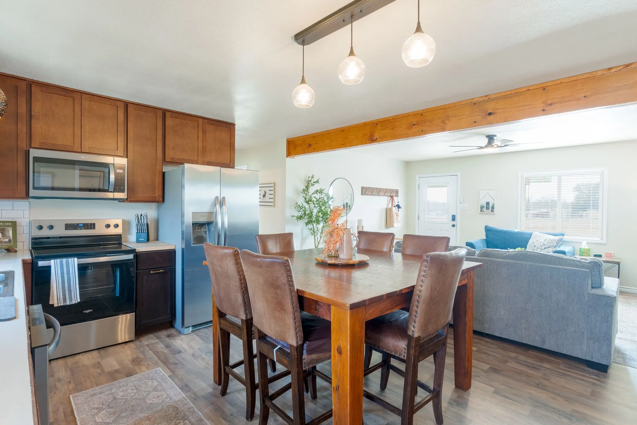 Dining space with light wood finished floors, ceiling fan, and beam ceiling
