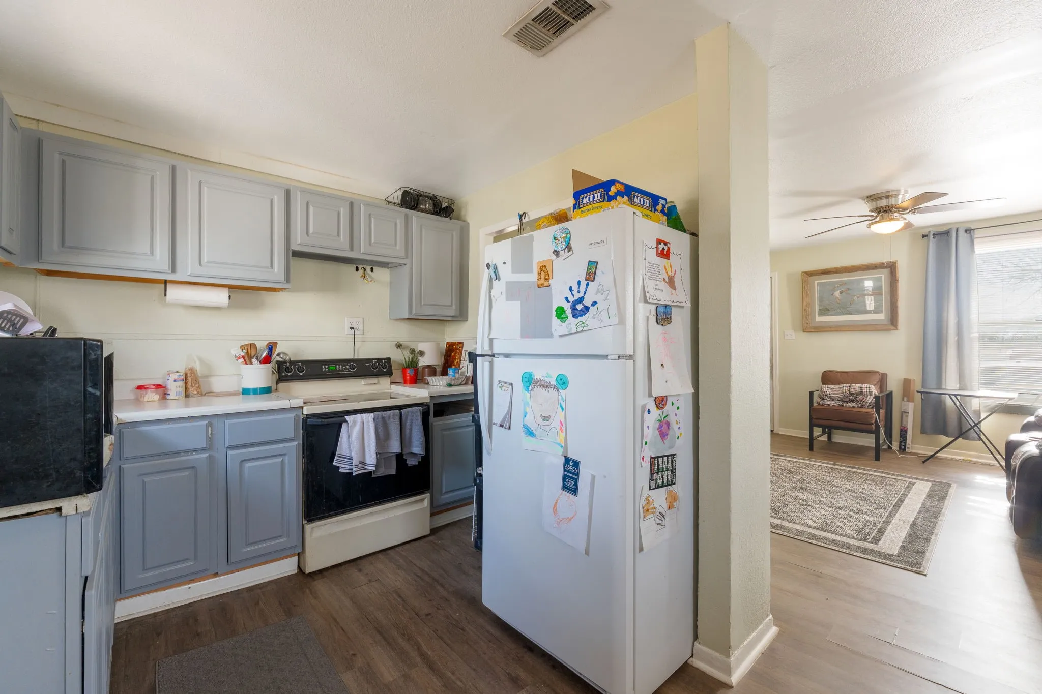 Kitchen featuring freestanding refrigerator, range with electric stovetop, dark wood-style flooring, light countertops, and gray cabinetry