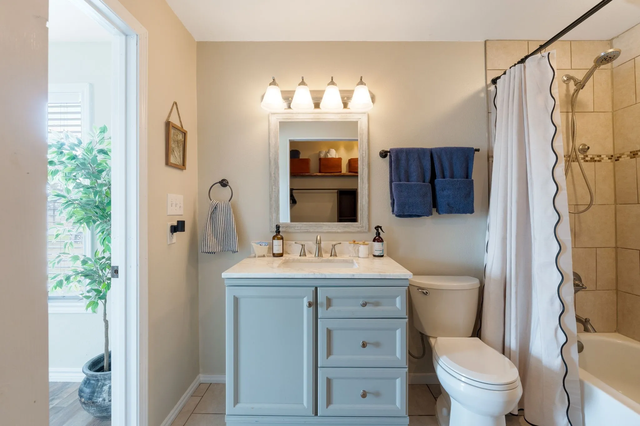 Bathroom with vanity, shower / bathtub combination with curtain, and light tile patterned floors
