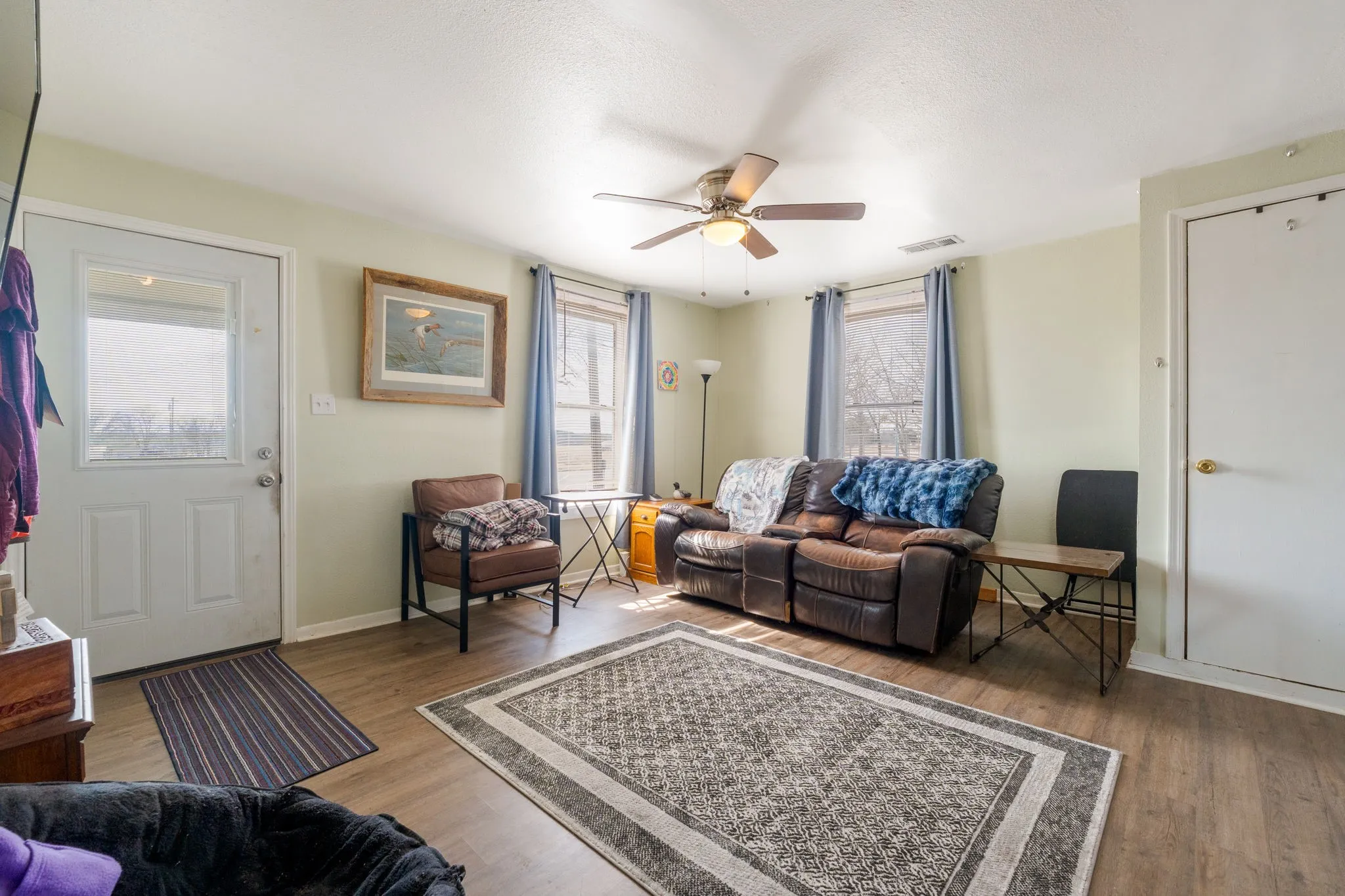 Living area featuring light wood-type flooring and a ceiling fan