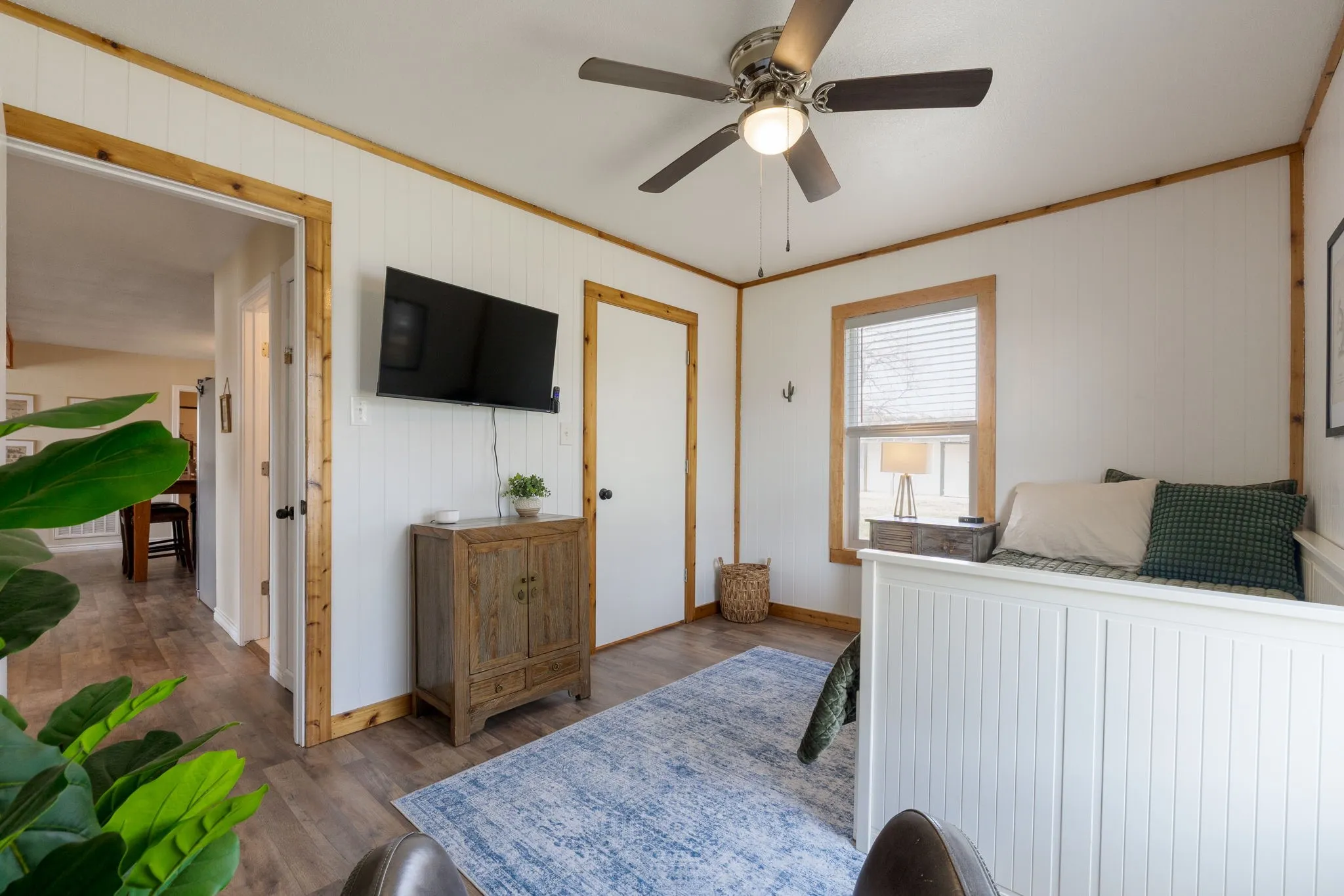 Bedroom with crown molding, wood walls, a ceiling fan, and wood finished floors