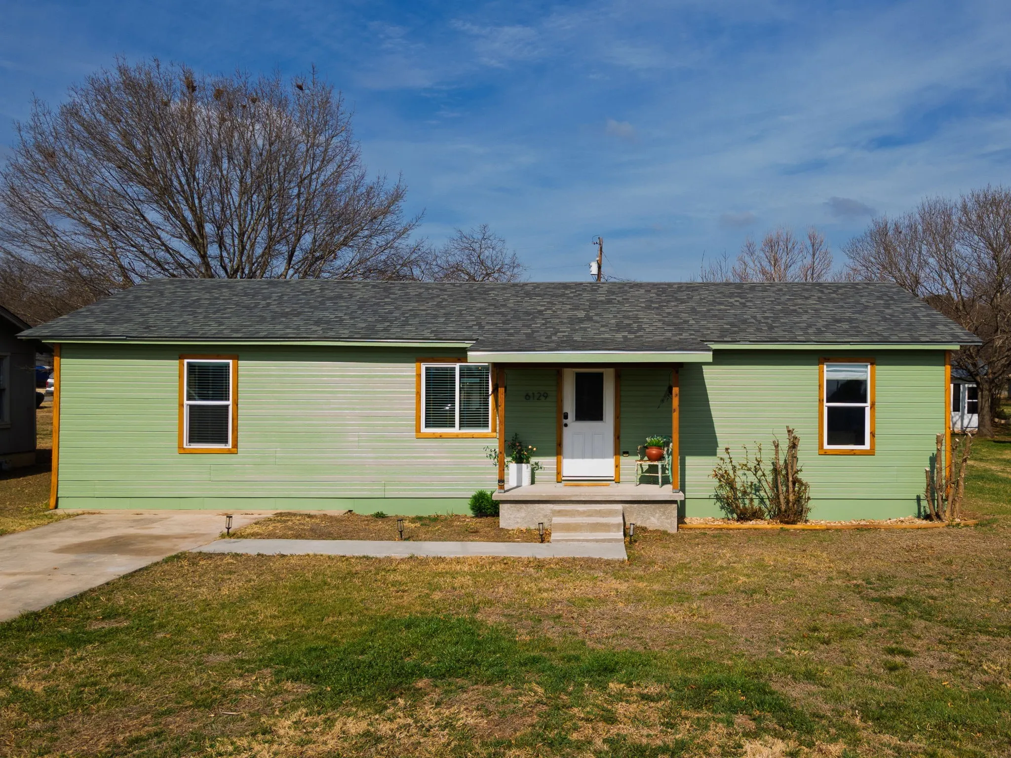 Ranch-style home with a porch, a front lawn, and roof with shingles