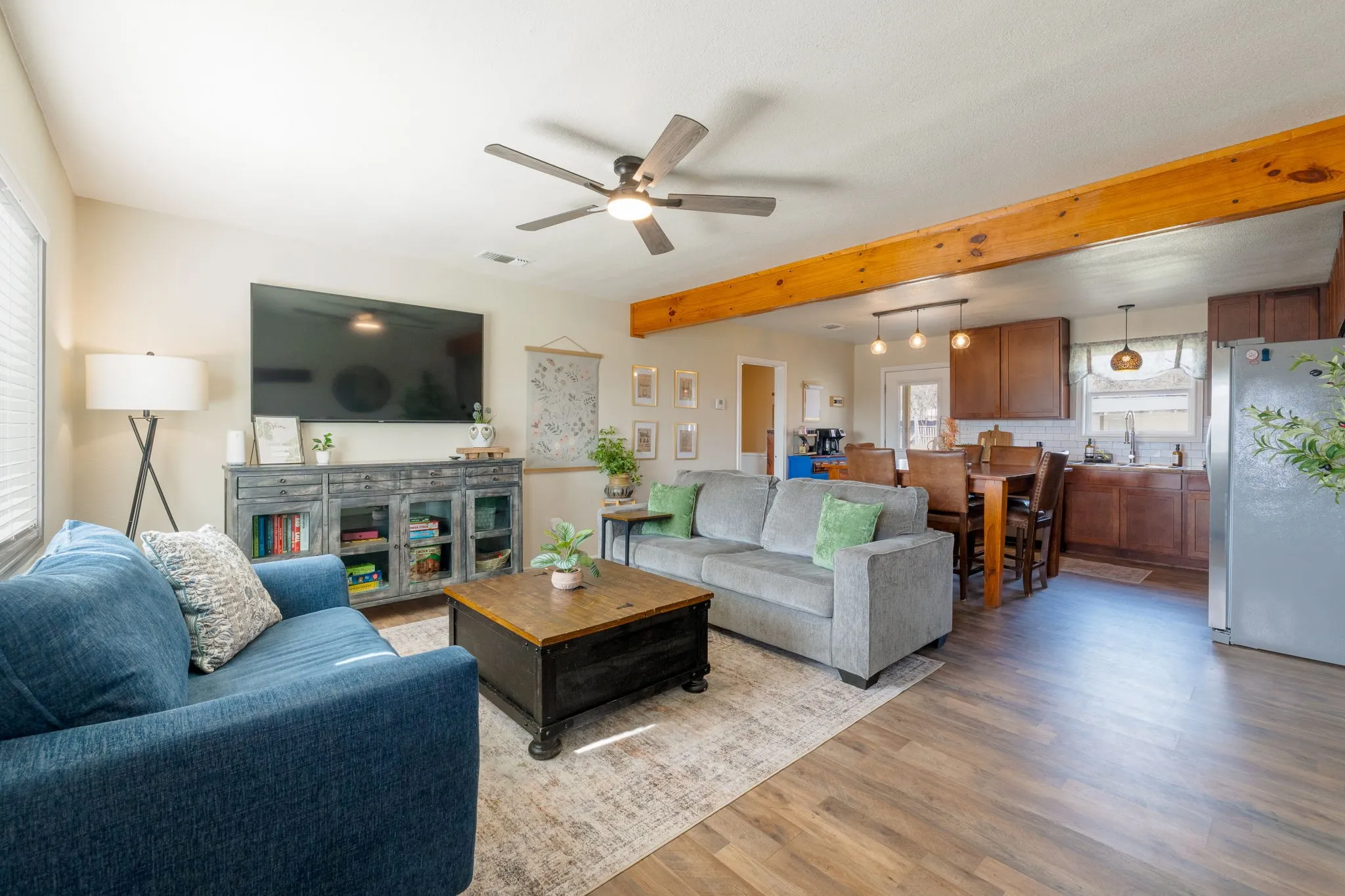 Living room with a ceiling fan, light wood-style flooring, and beamed ceiling