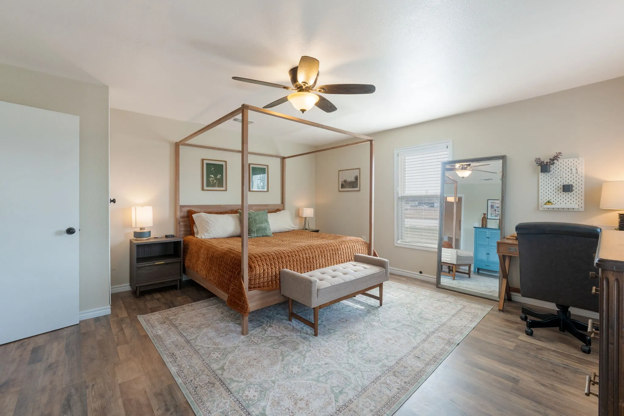 Bedroom with dark wood-style floors, ceiling fan, and an office area