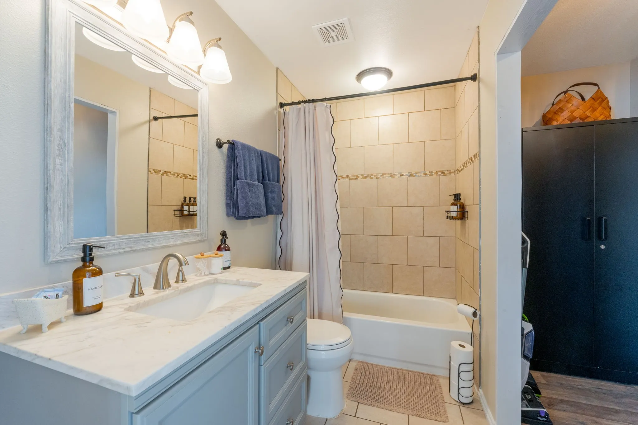 Full bath featuring vanity, shower / bath combo with shower curtain, and light tile patterned floors