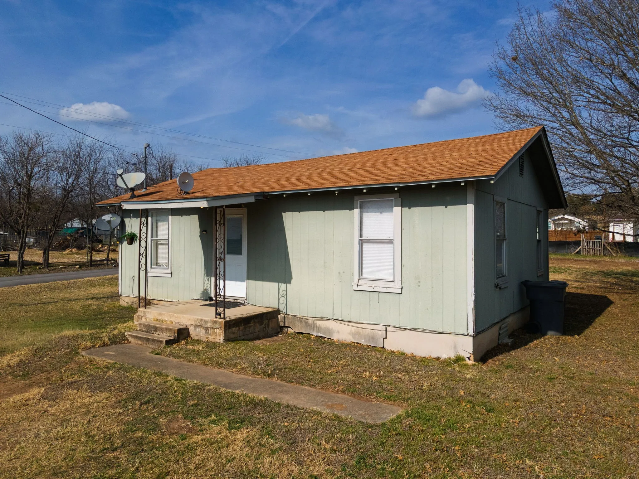 View of front of home with a front lawn and a shingled roof