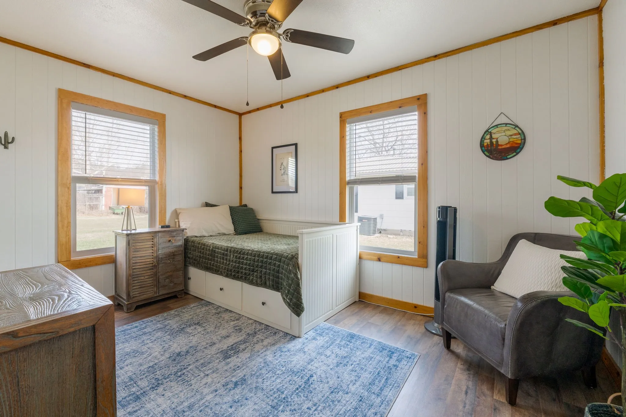 Bedroom with dark wood-style flooring, a ceiling fan, crown molding, and wooden walls