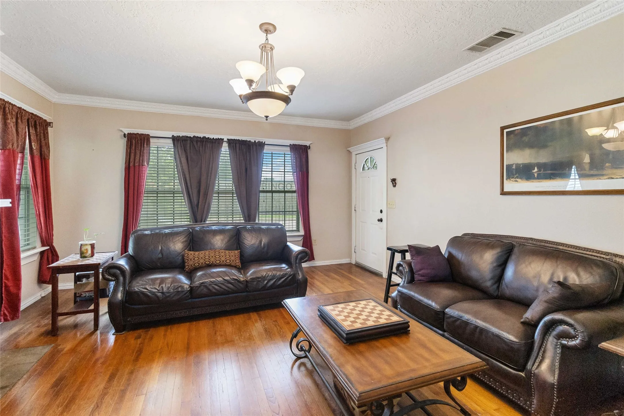 Living area with hardwood / wood-style floors, a textured ceiling, suspended lighting, and ornamental molding