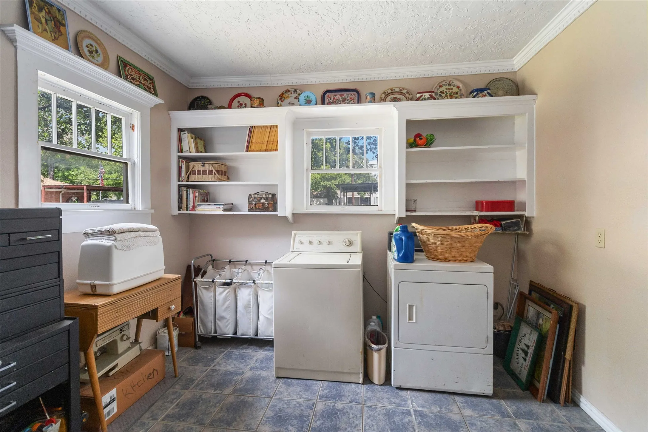 Laundry room with crown molding, washing machine and dryer, a textured ceiling, and healthy amount of natural light
