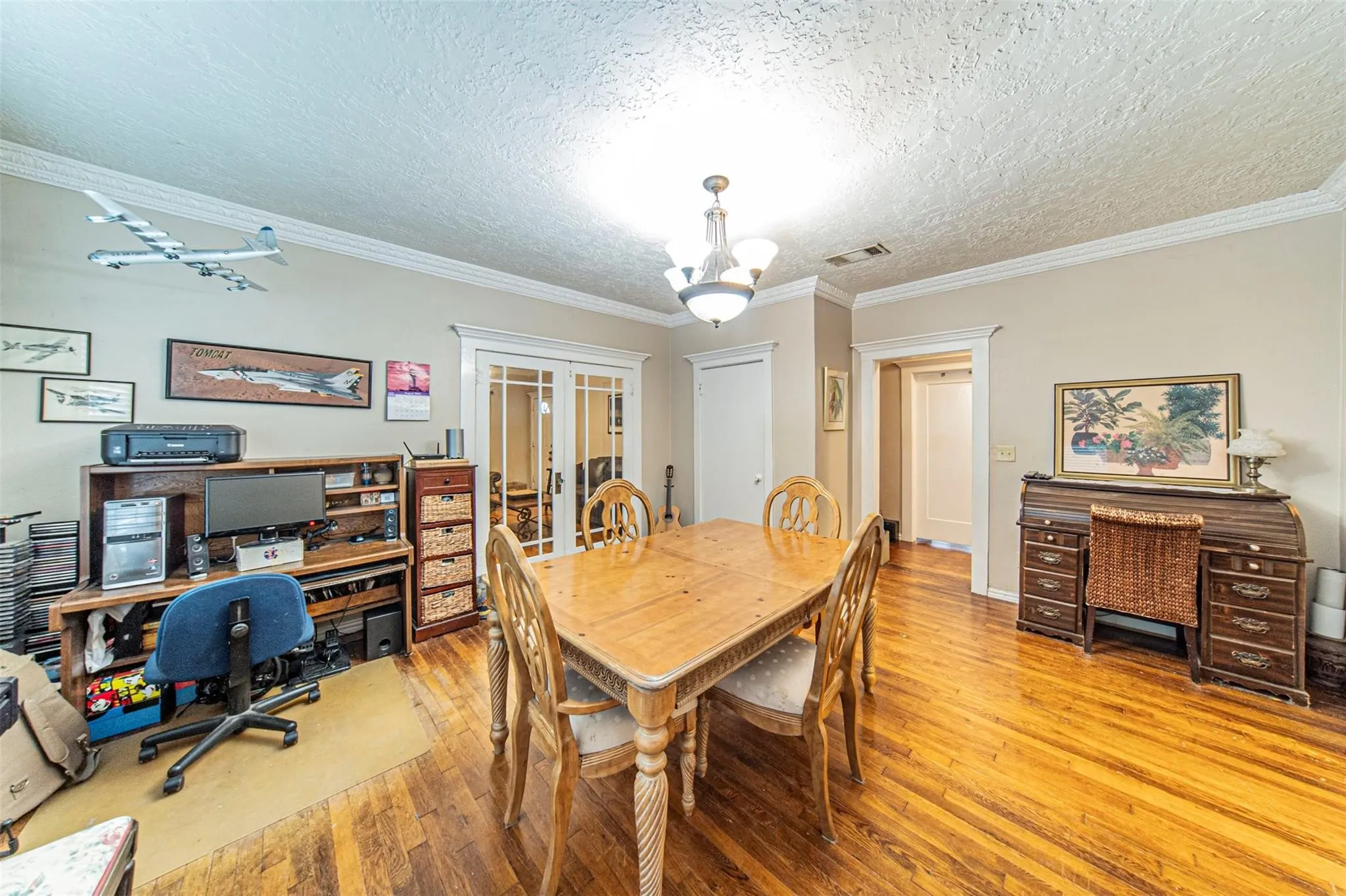 Dining space featuring hardwood / wood-style flooring, crown molding, an office area, a textured ceiling, and suspended lighting