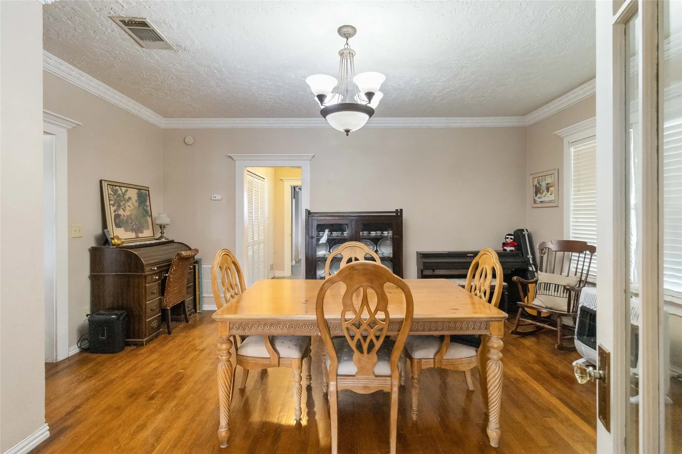 Dining area featuring a textured ceiling, hanging lights, wood finished floors, and crown molding