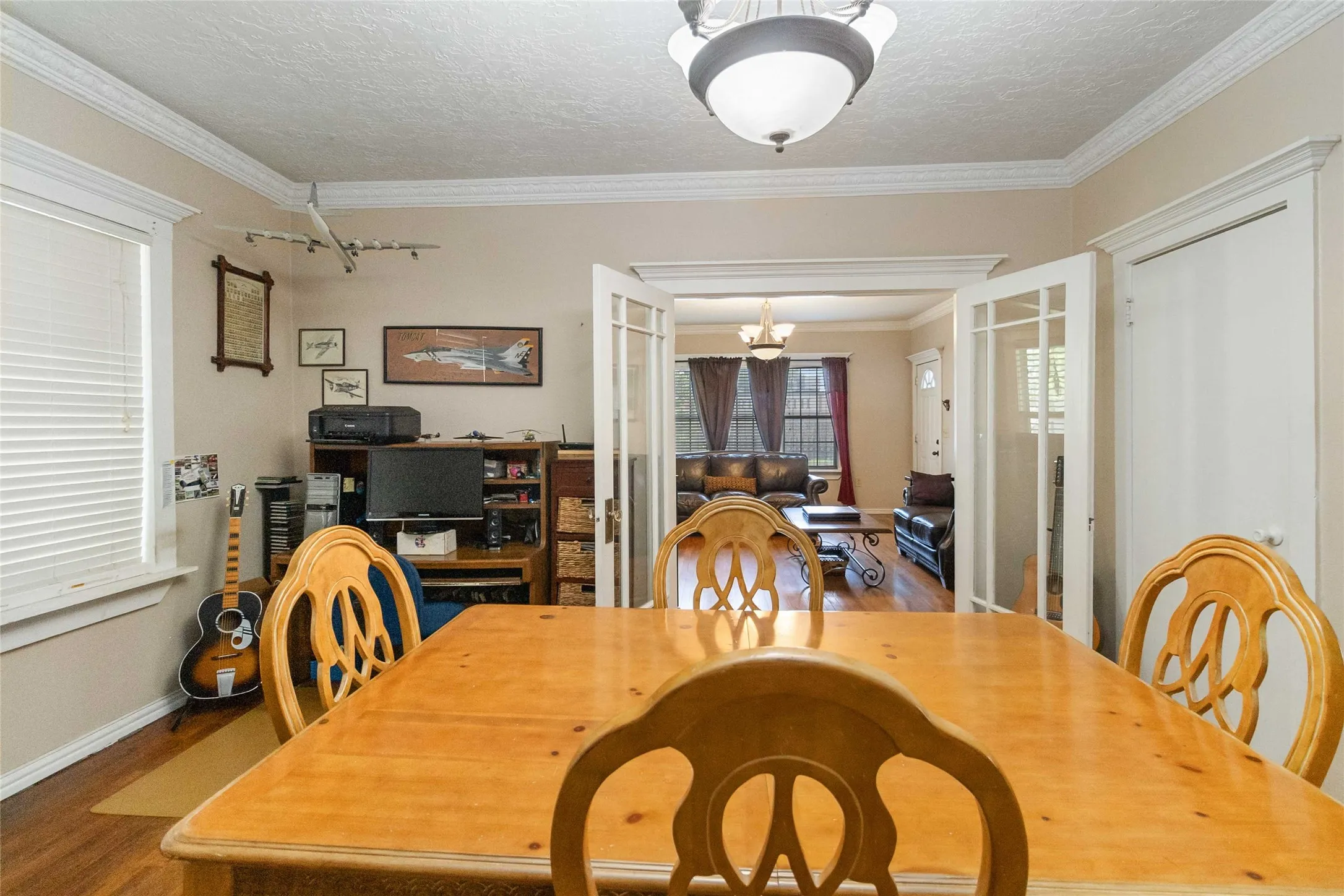 Dining room featuring suspended lighting, a textured ceiling, ornamental molding, french doors, and wood finished floors