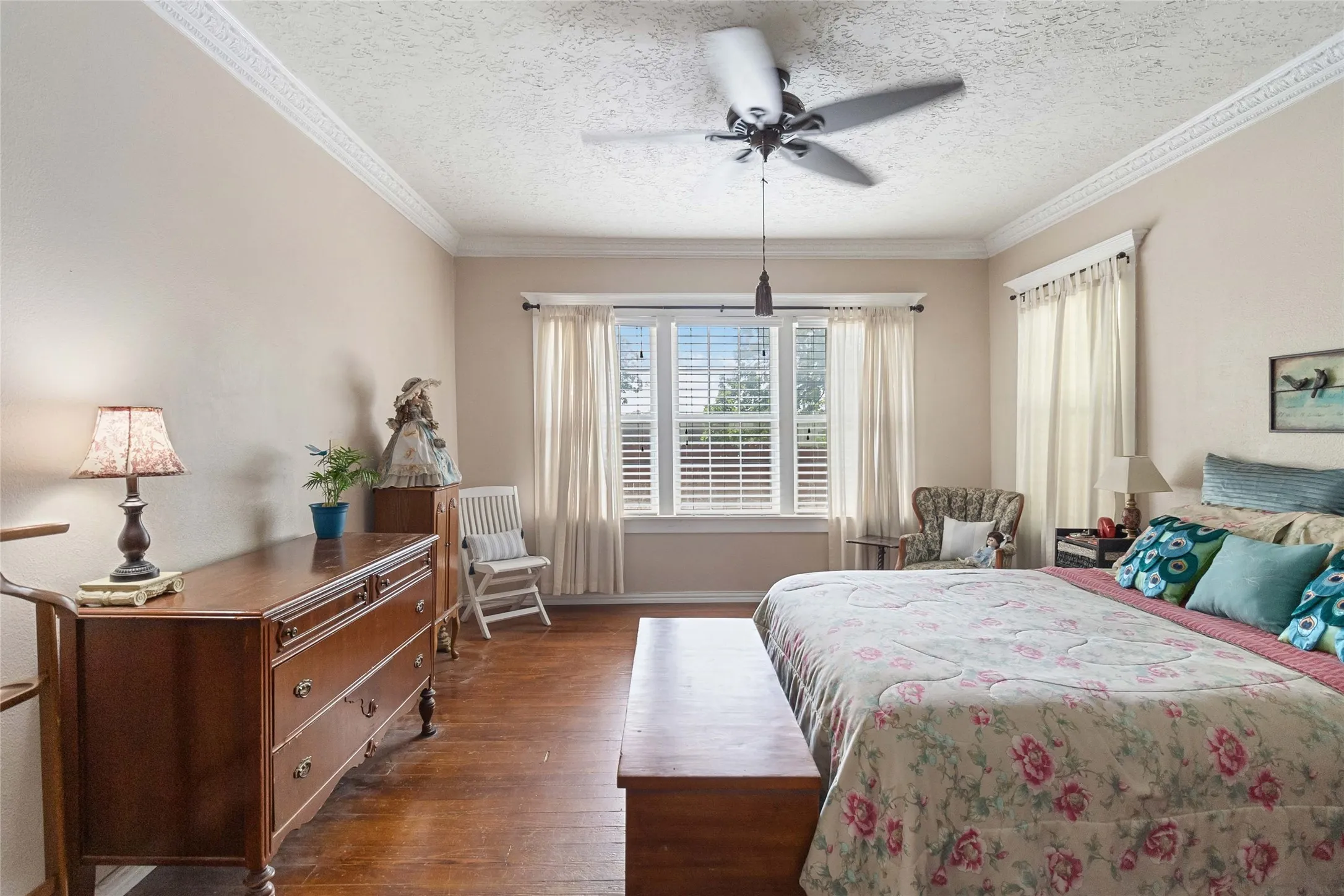 Bedroom featuring hardwood / wood-style floors, a ceiling fan, a textured ceiling, and ornamental molding