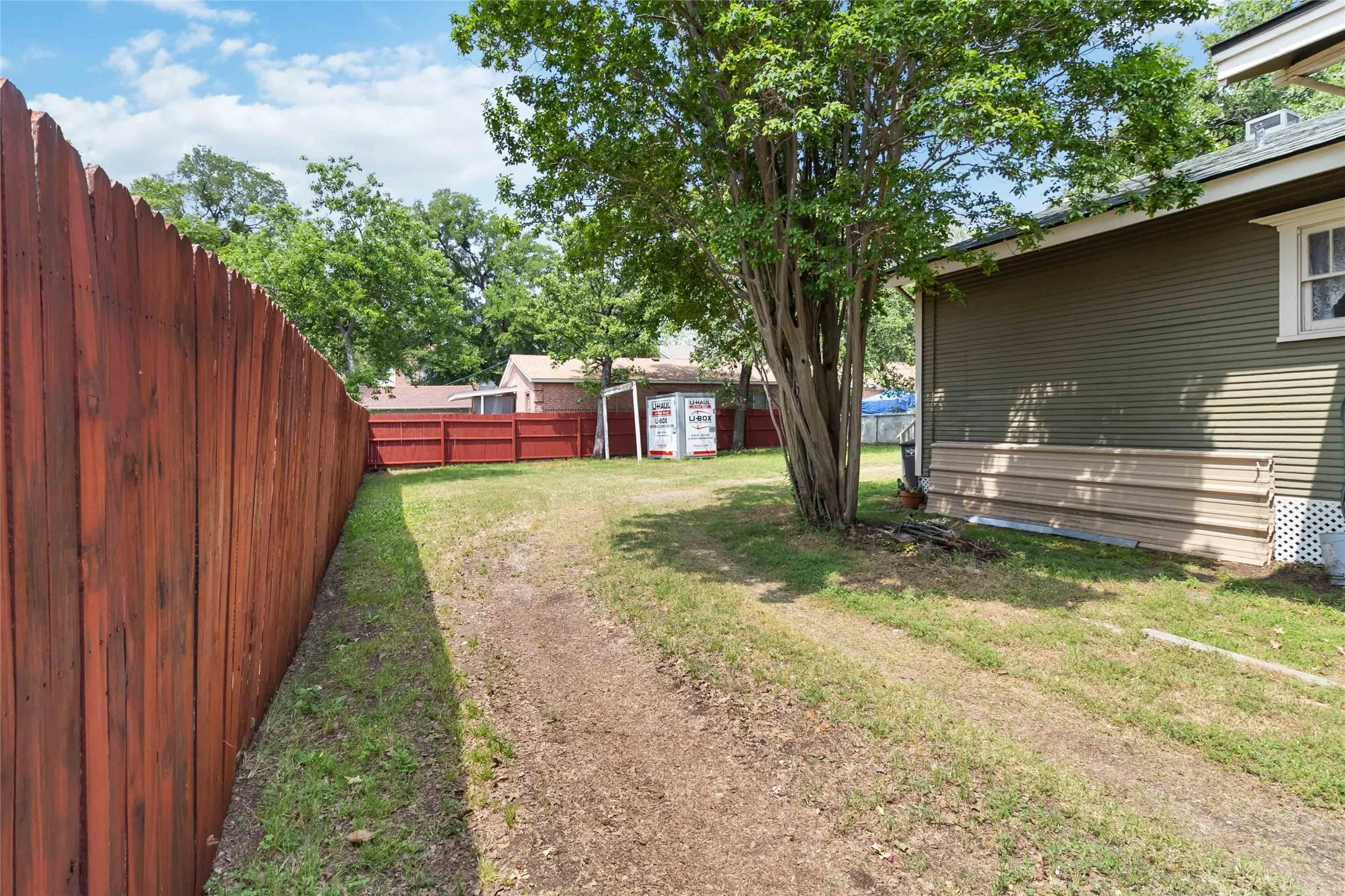 Fenced backyard featuring a storage unit