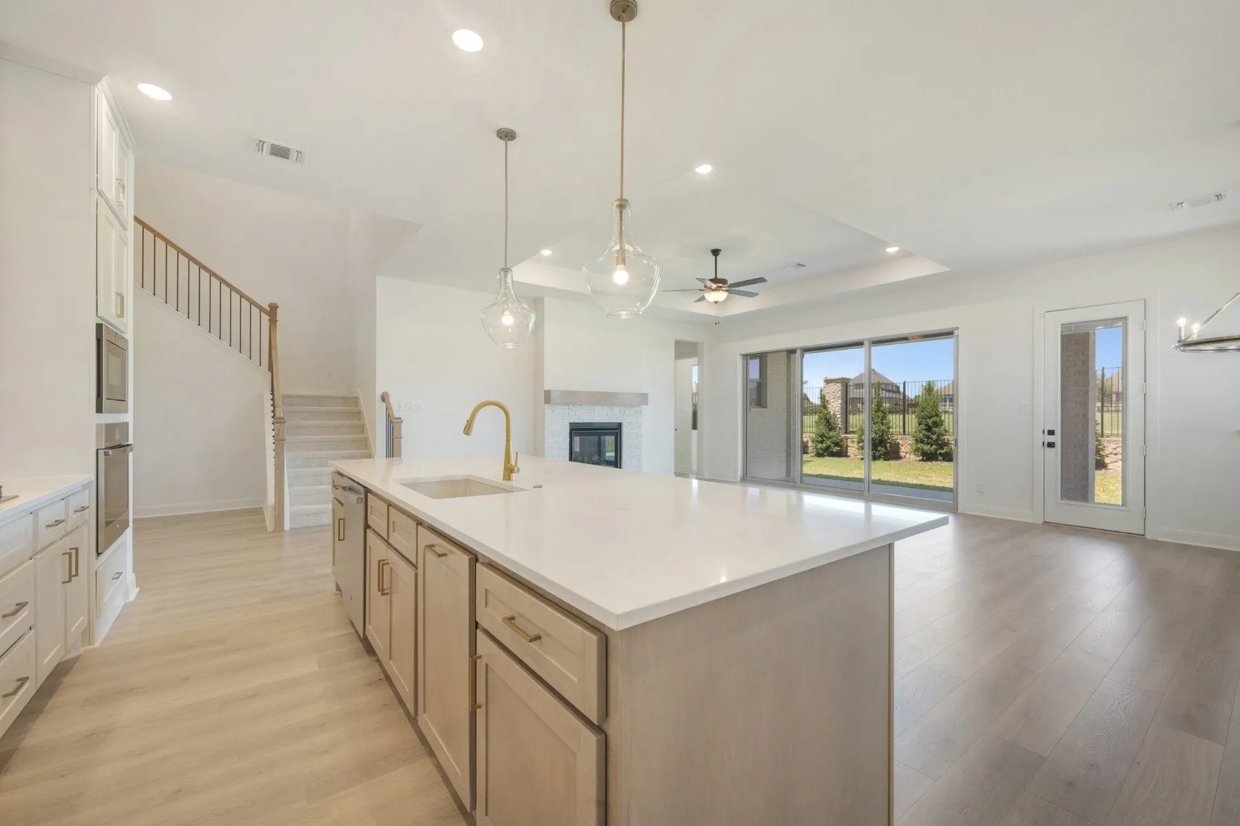 Expansive kitchen island with a light-toned countertop, brass-finish faucet, and pendant lighting