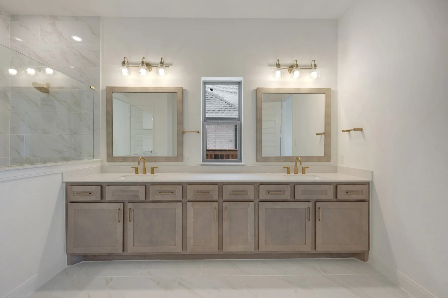 Dual vanity featuring light wood-finish cabinetry, white countertops, and gold-toned fixtures