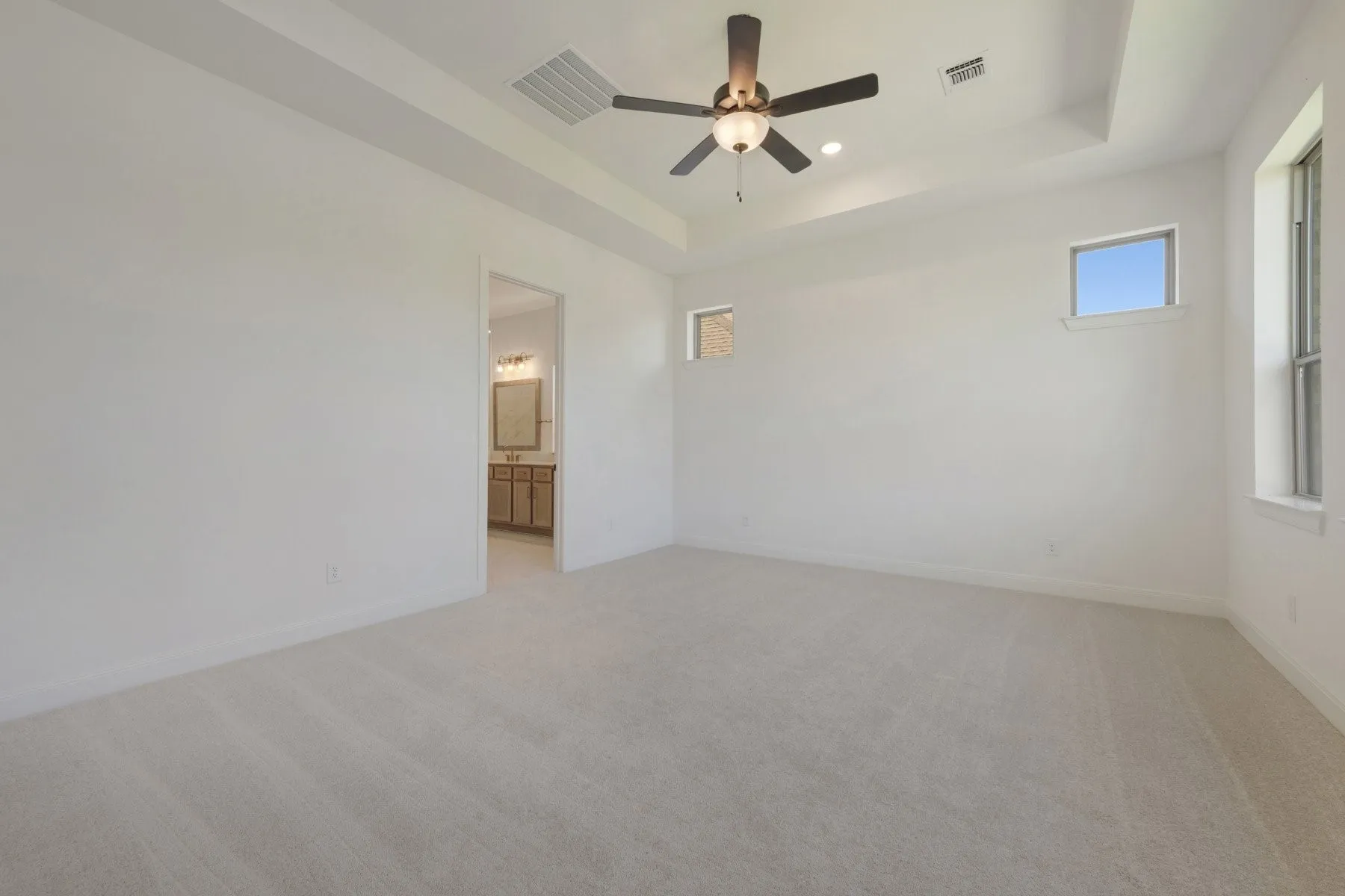 Spacious room featuring light-toned carpeting and a tray ceiling