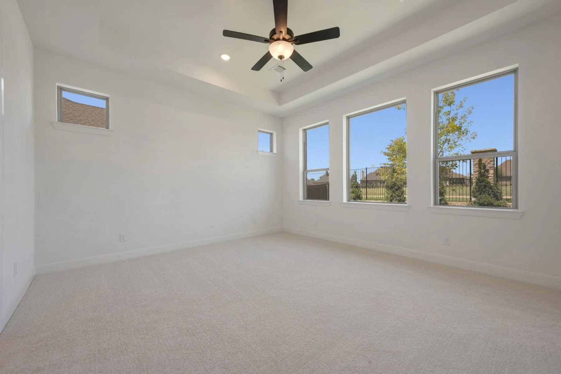 Spacious room featuring light-toned carpeting and multiple windows