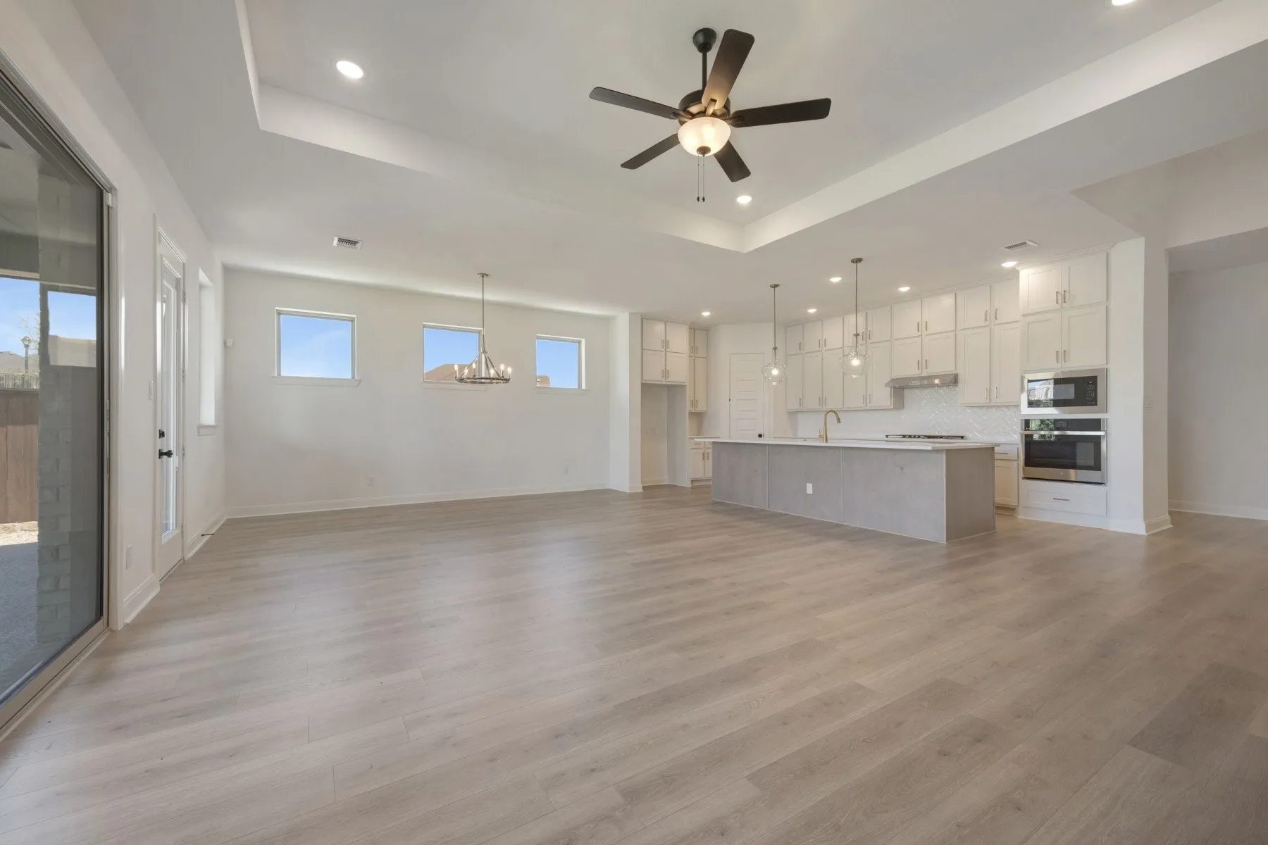 Open-concept living space featuring wood-finish flooring, recessed lighting, and a tray ceiling