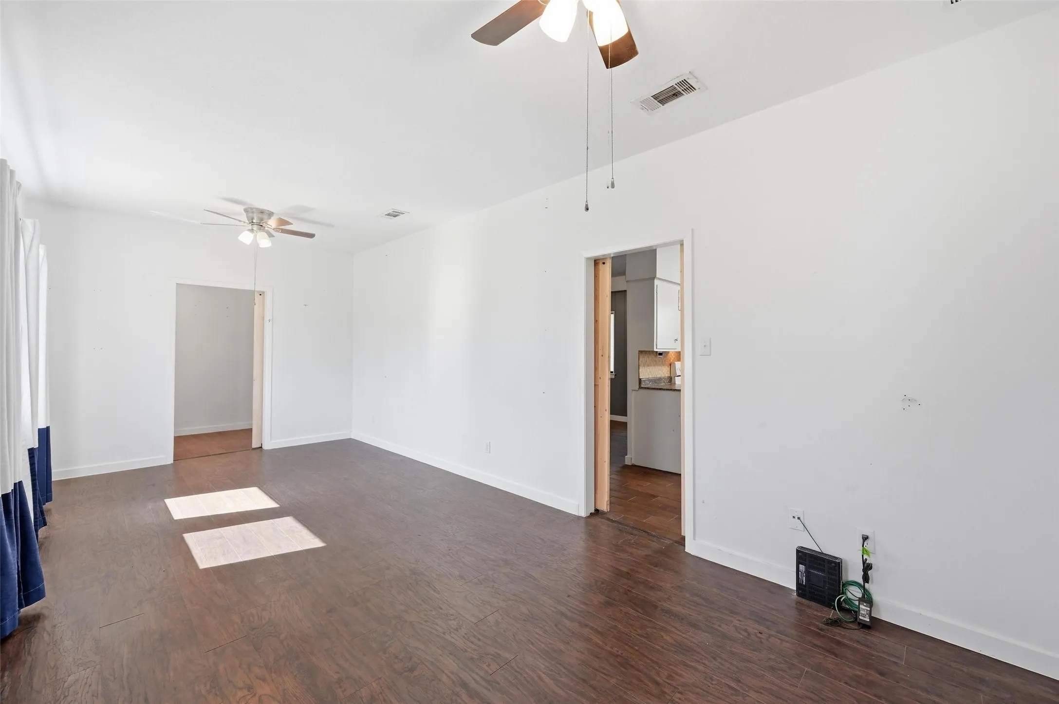 Empty room with a ceiling fan and dark wood finished floors