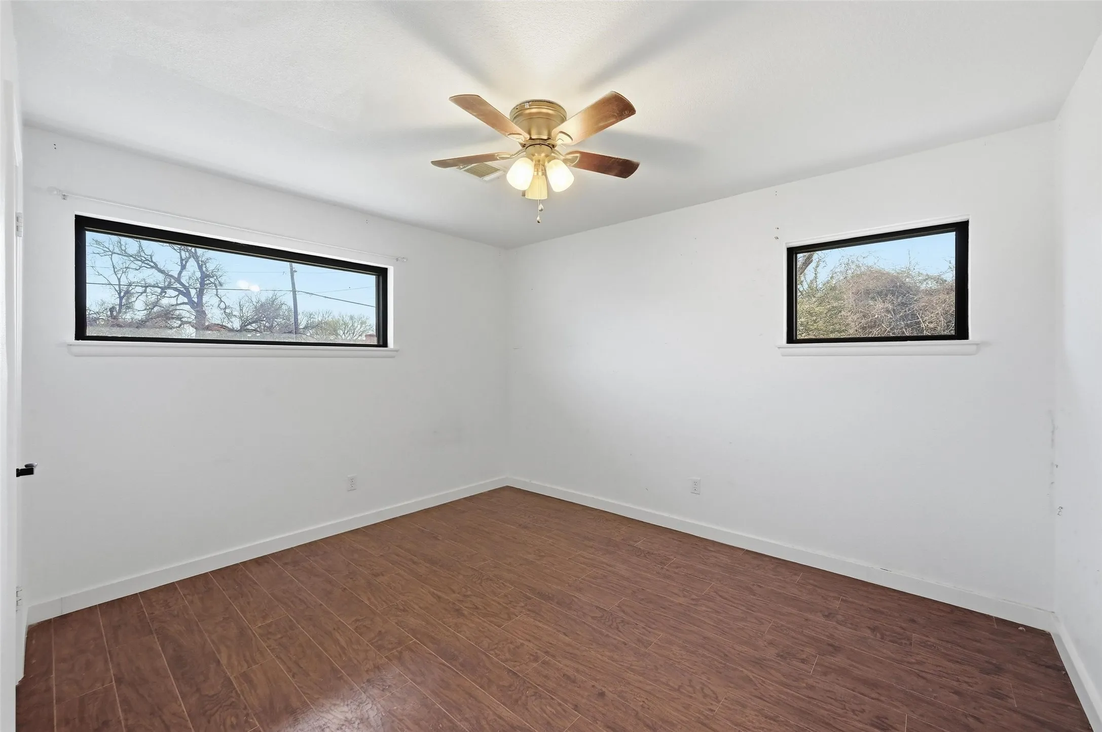 Empty room with dark wood-style floors and ceiling fan