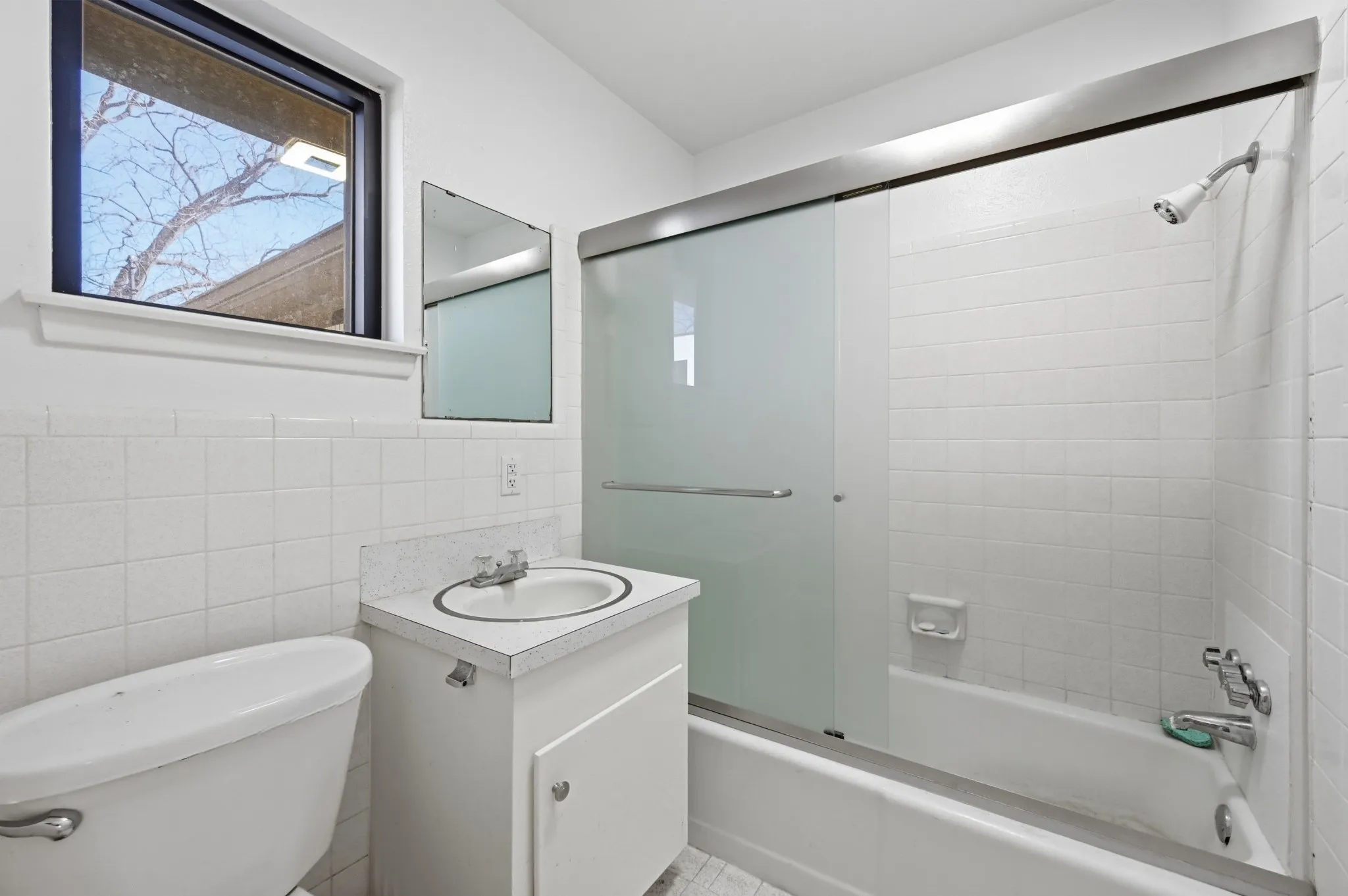 Bathroom with vanity, tile walls, and enclosed tub / shower combo