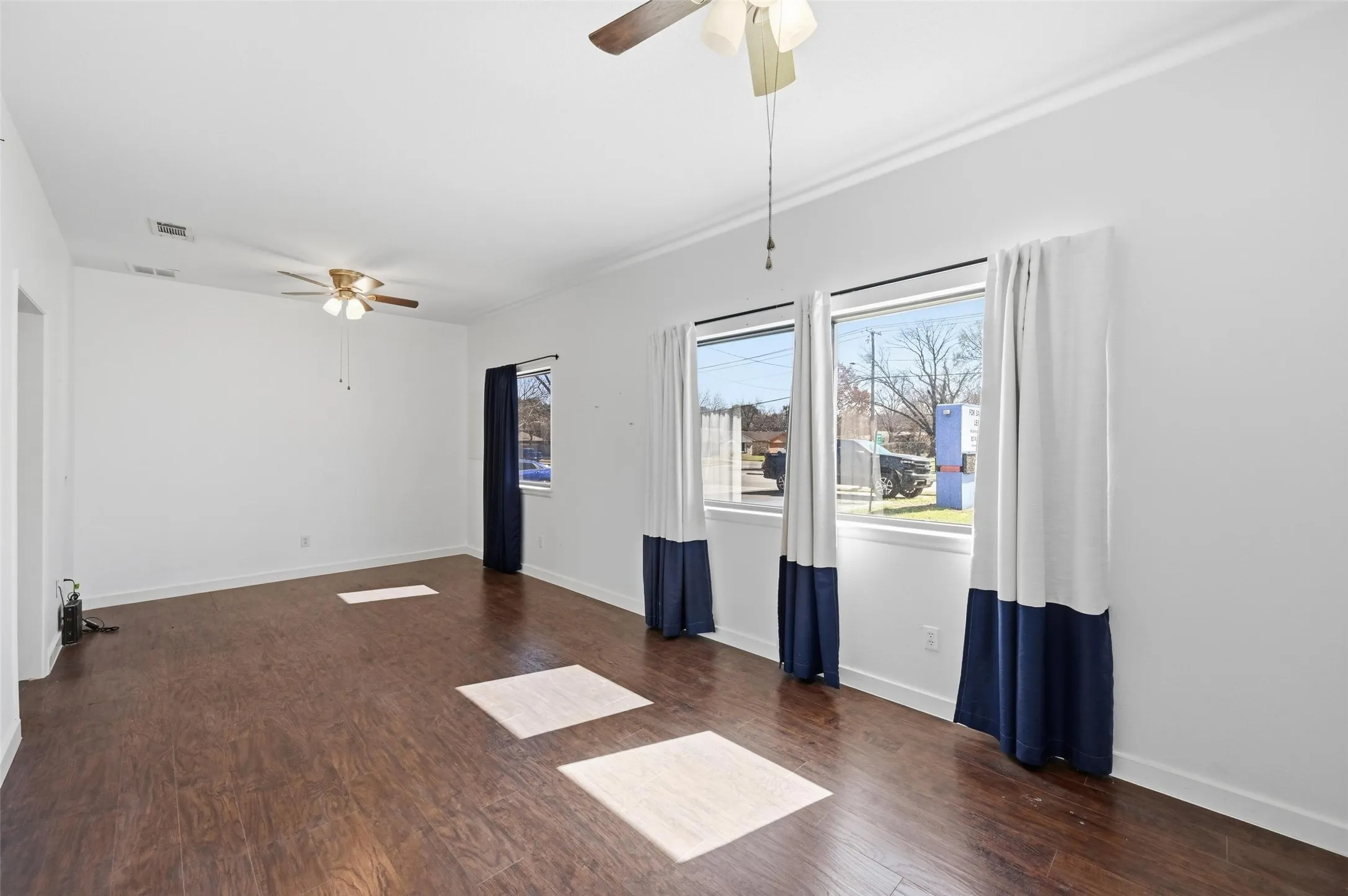 Empty room featuring ceiling fan and dark wood-style flooring