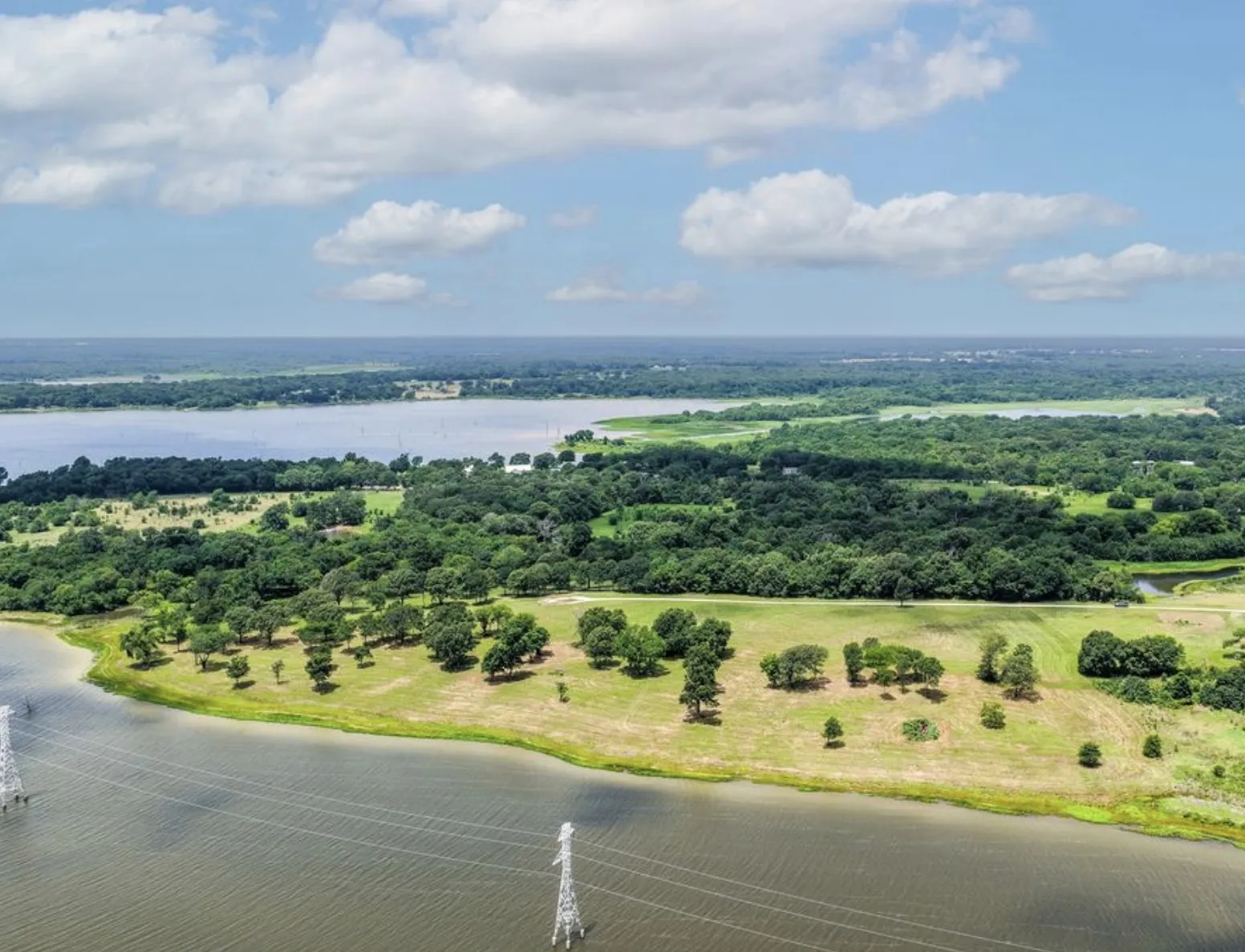 Expansive waterfront parcel featuring mature trees, open grassy areas, and direct water access