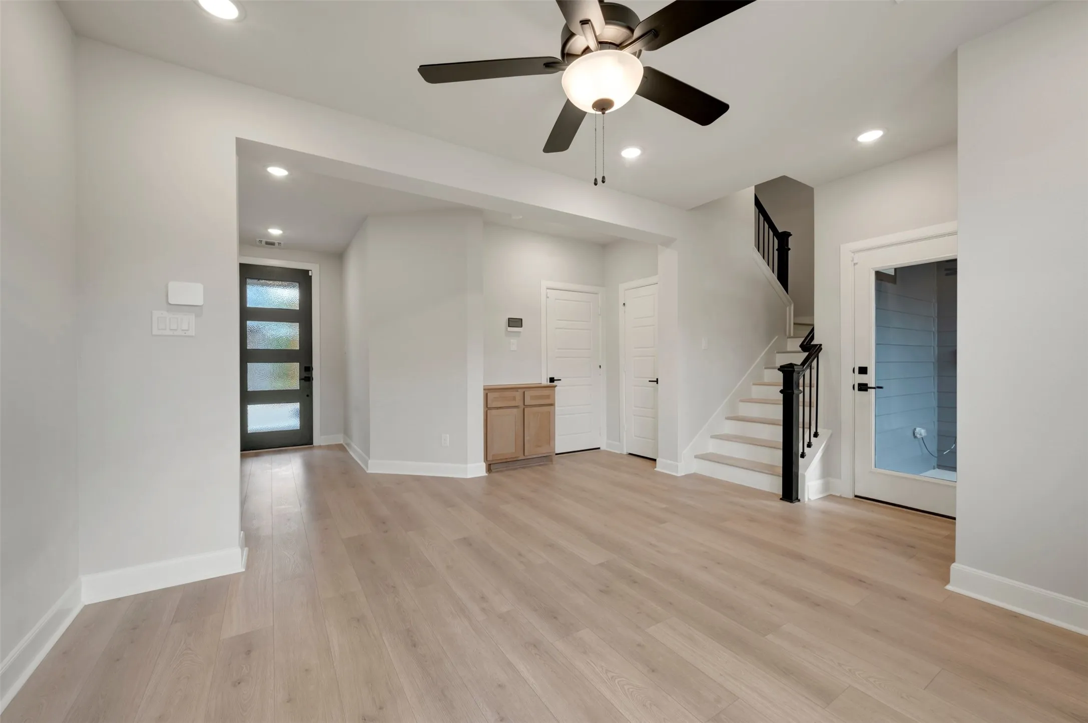 Light wood-finish flooring with recessed lighting and a ceiling fan