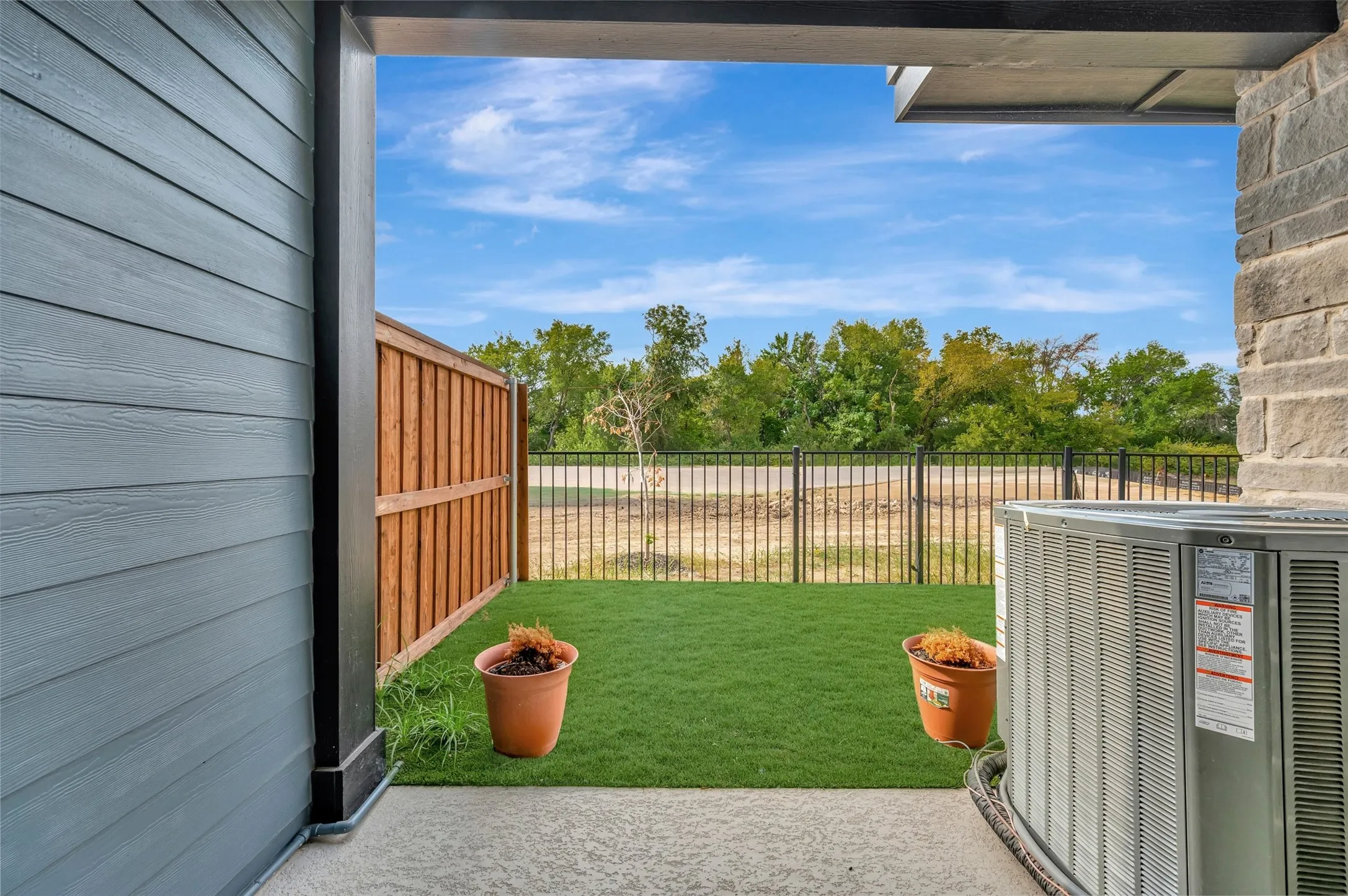 Private outdoor area featuring artificial turf, a wood privacy fence, and a black metal fence