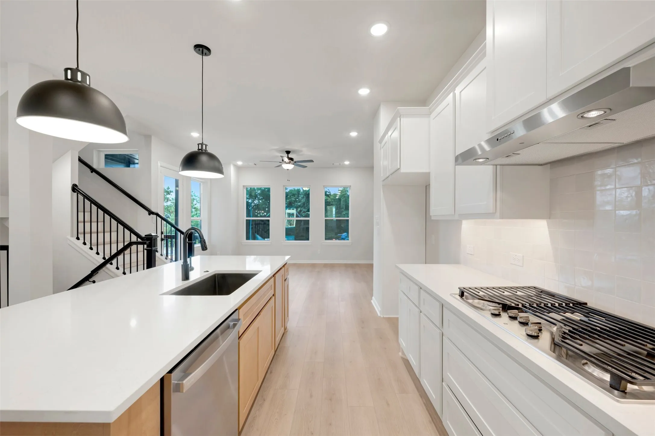 Expansive kitchen island with an undermount sink, stainless steel dishwasher, and quartz countertops