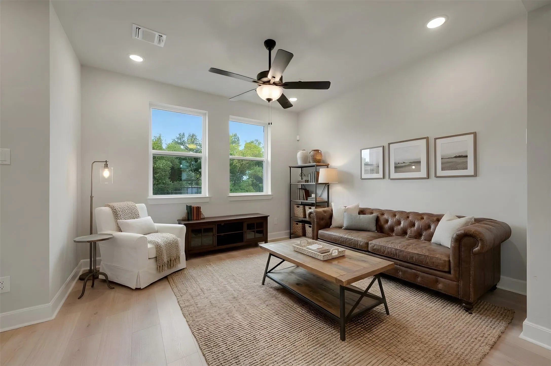Recessed lighting, light wood-finish flooring, two large windows, ceiling fan with integrated lighting, and high ceilings