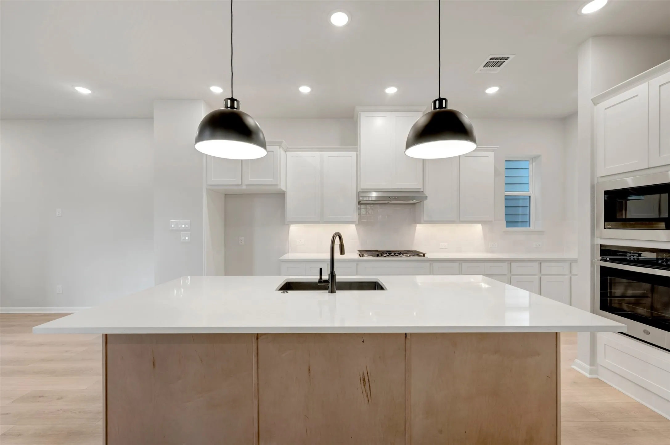 Kitchen island with a white countertop and integrated sink, complemented by dual pendant lights