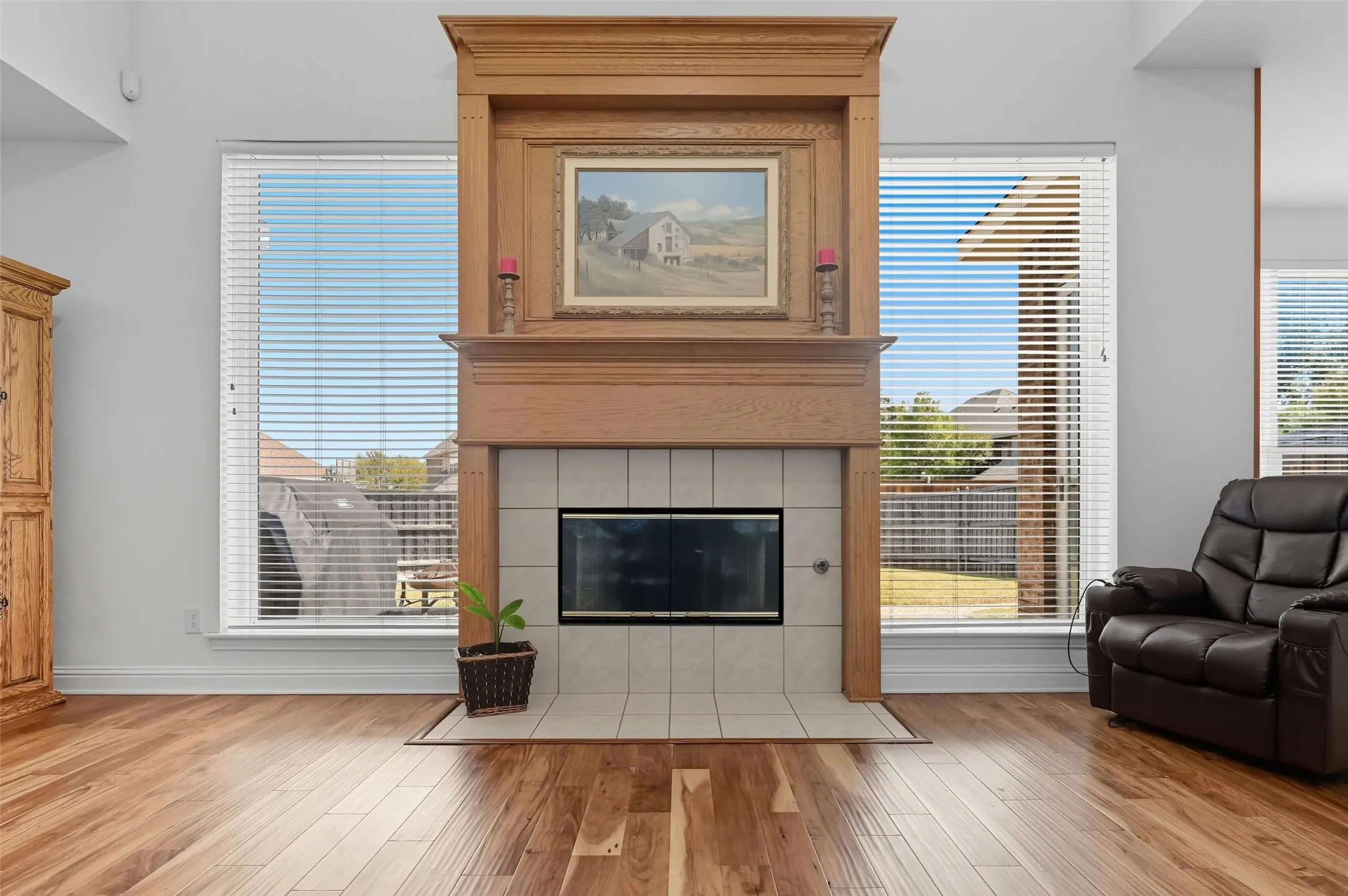 Striking double-stacked oak fireplace serves as the focal point of the room, beautifully framed by expansive windows that fill the space with natural light.