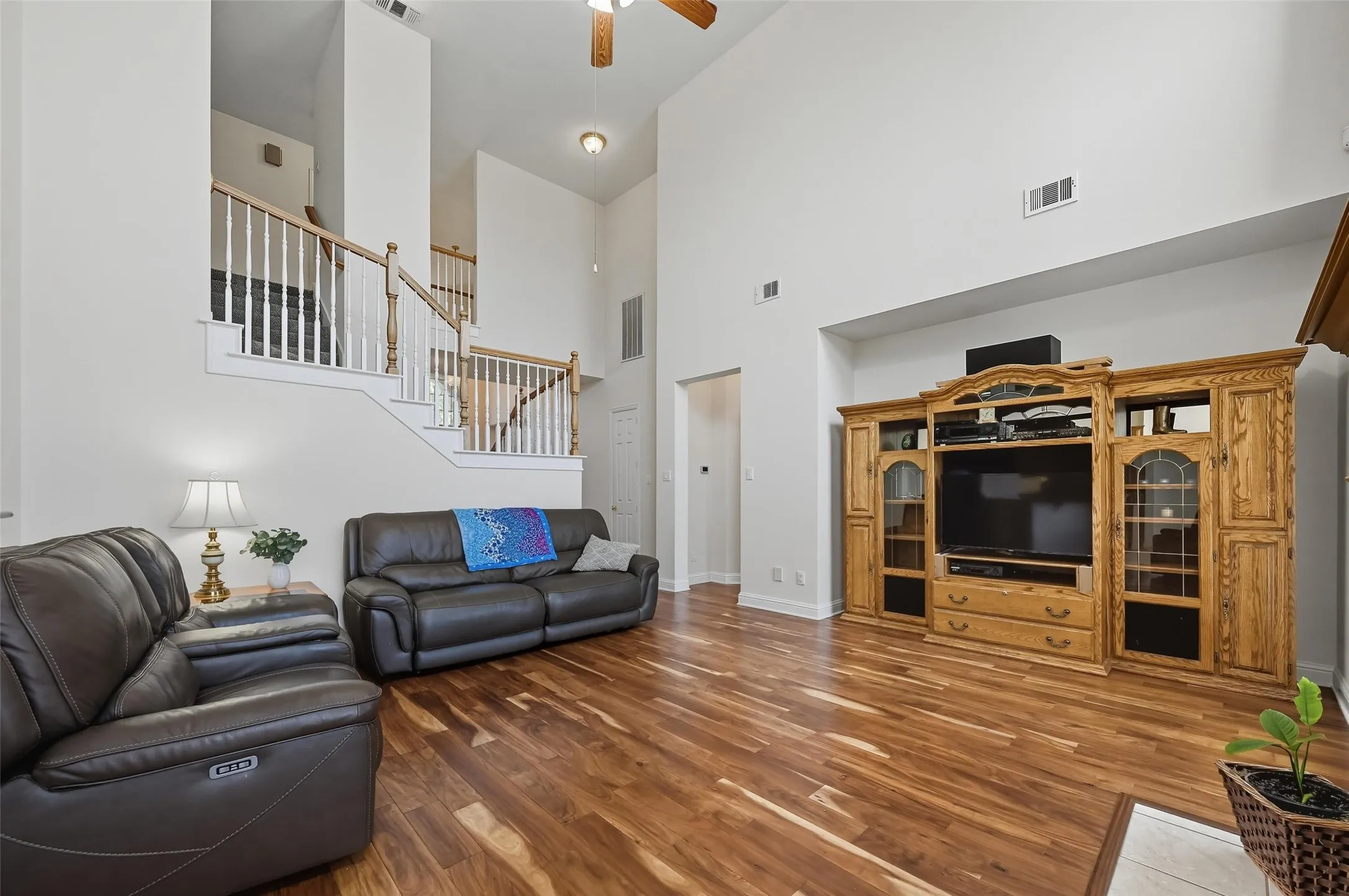 Impressive living room with soaring two-story ceilings, a beautiful staircase, and an open-concept design that flows seamlessly into the kitchen—perfect for everyday living and entertaining.