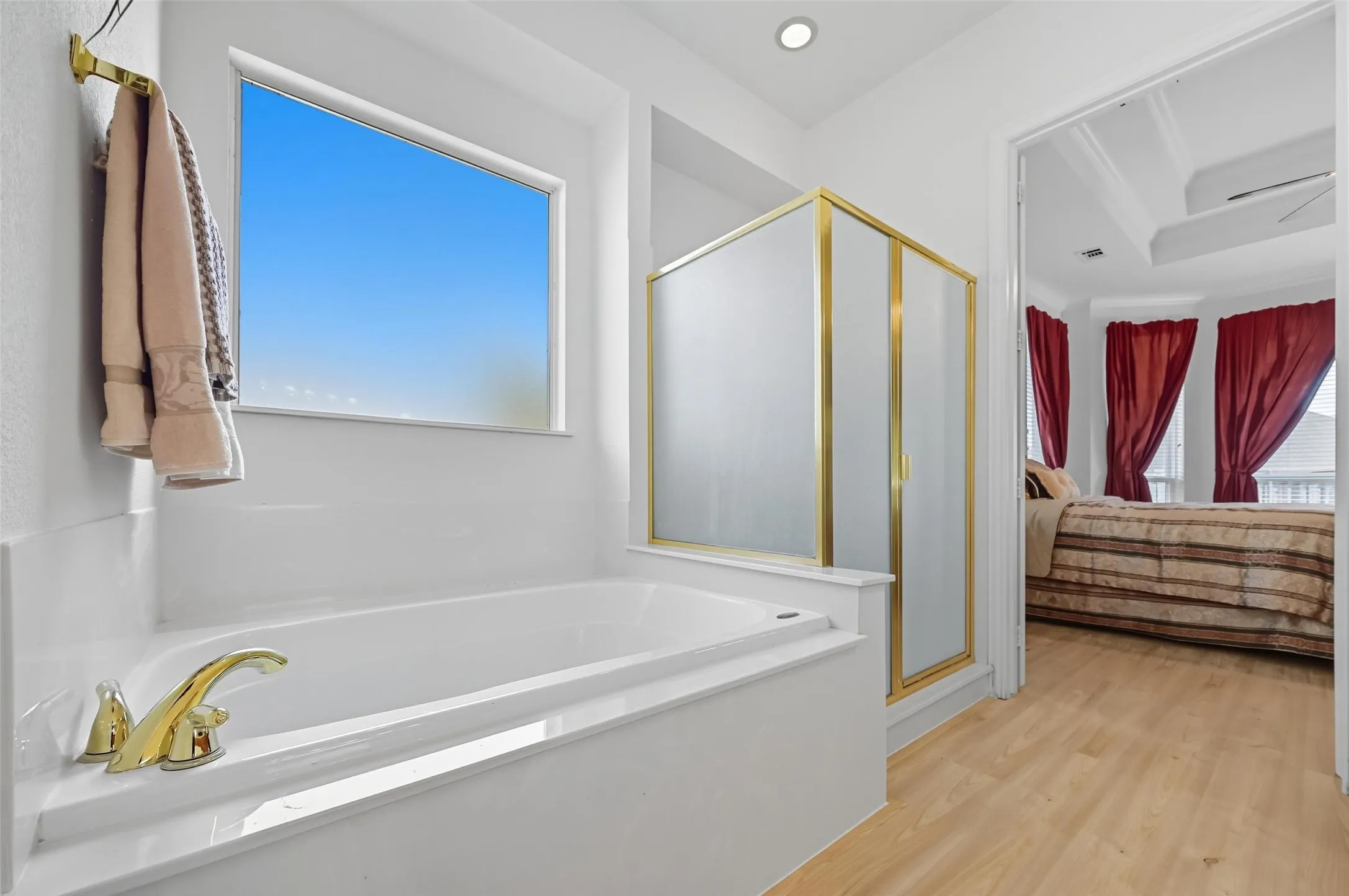 Spacious primary bath featuring dual sinks, an oversized corner vanity with abundant cabinet storage, a separate shower, and a walk-in closet with upper tier for seasonal clothing.