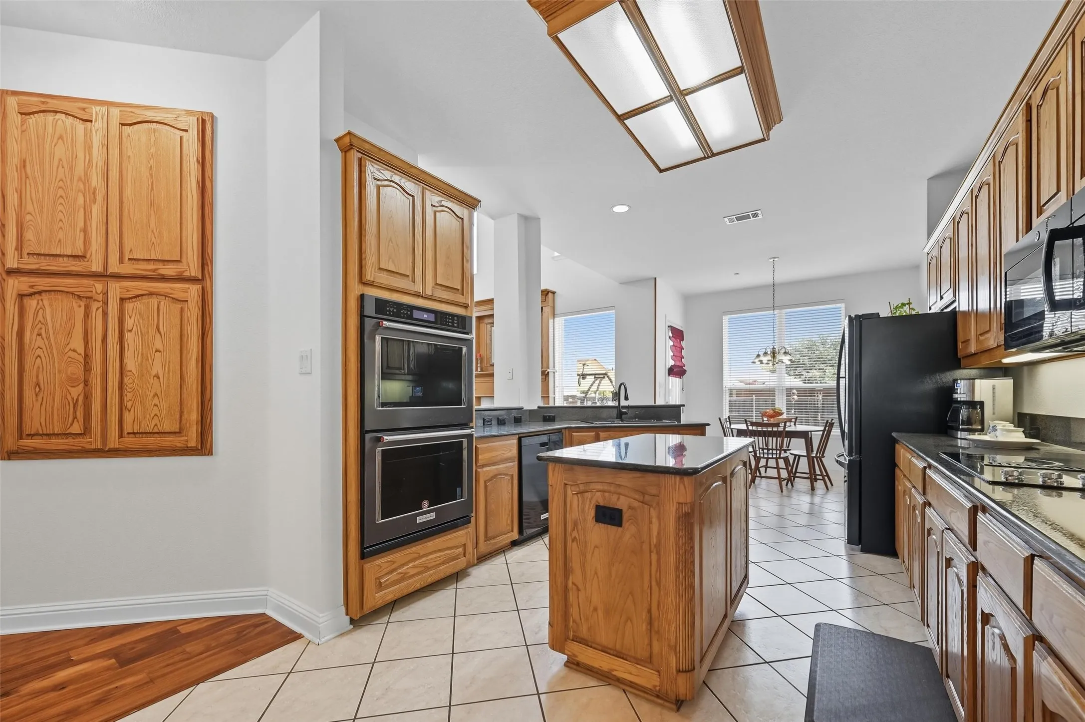 Chef-inspired kitchen featuring rich dark granite countertops, a spacious island with storage and electrical access, double ovens, and an oversized walk-in pantry for exceptional storage.