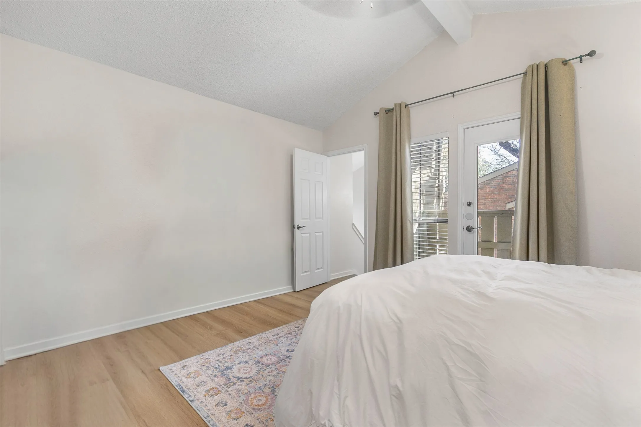 Bedroom featuring light wood finished floors, access to exterior, a ceiling fan, and beamed ceiling