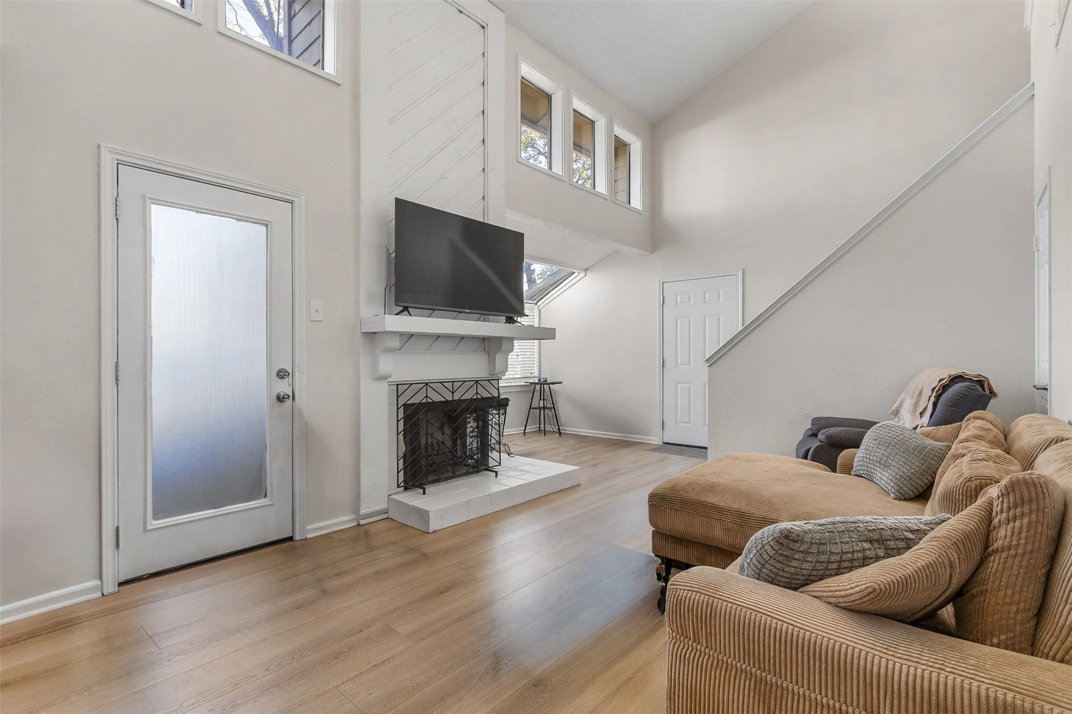 Living area featuring light wood finished floors, a tile fireplace, and vaulted ceiling