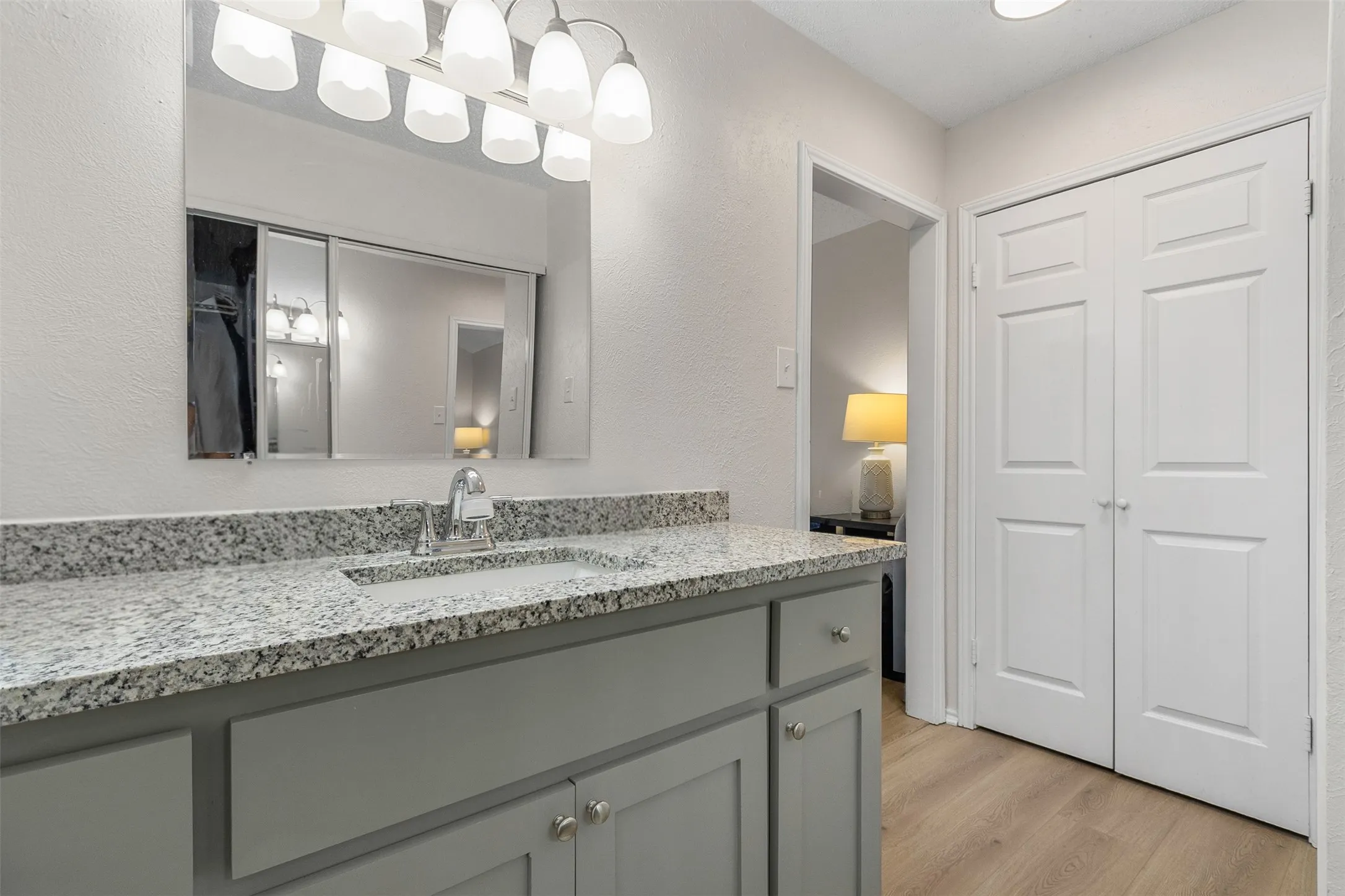 Bathroom featuring vanity, light wood-style floors, and a textured wall