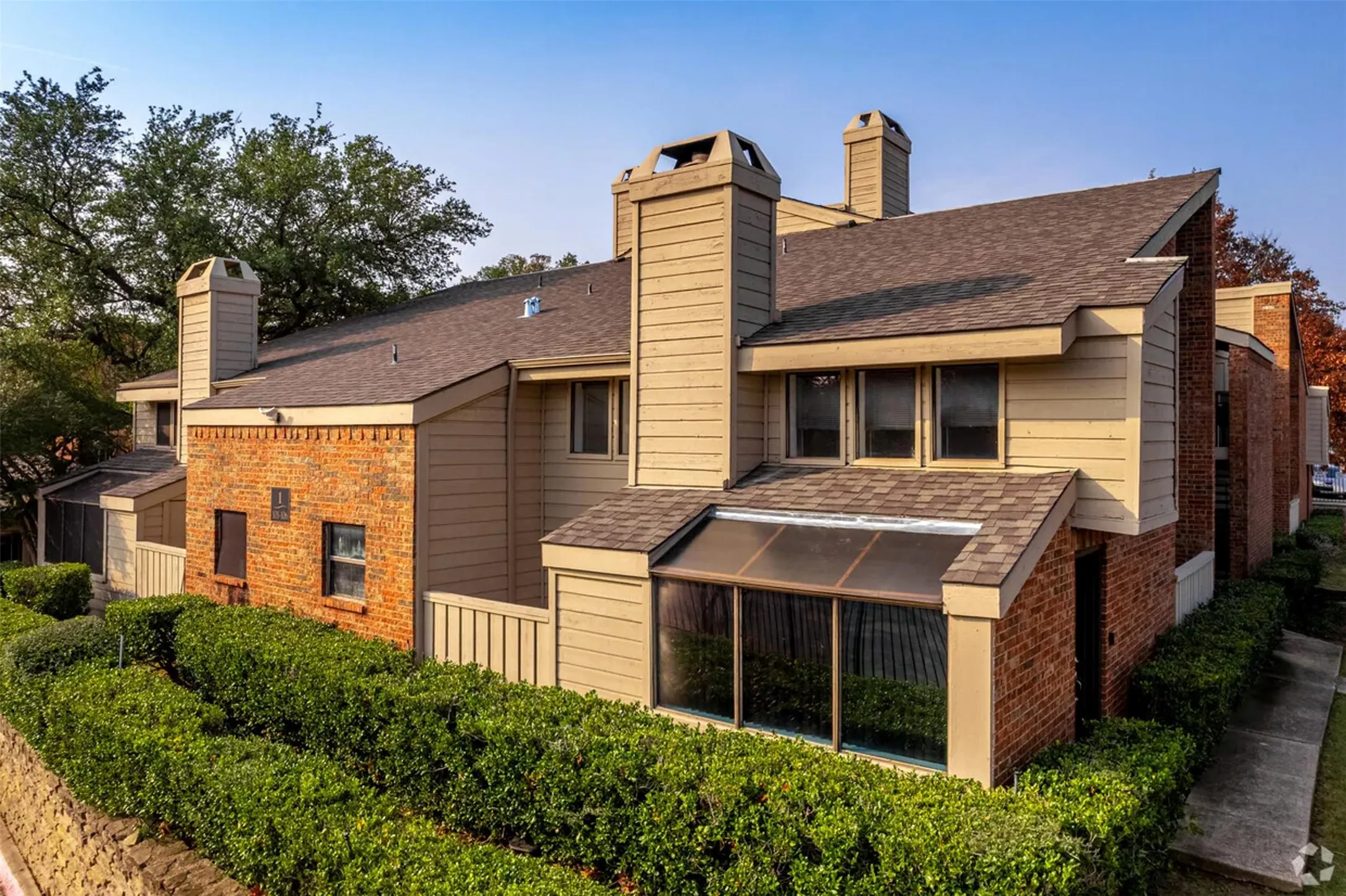 Rear view of house with brick siding, roof with shingles, and a chimney