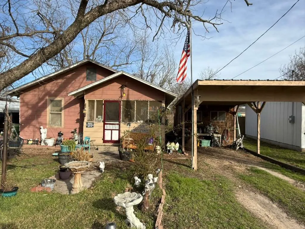 Rear view of property with a patio area, a yard, dirt driveway, and a carport