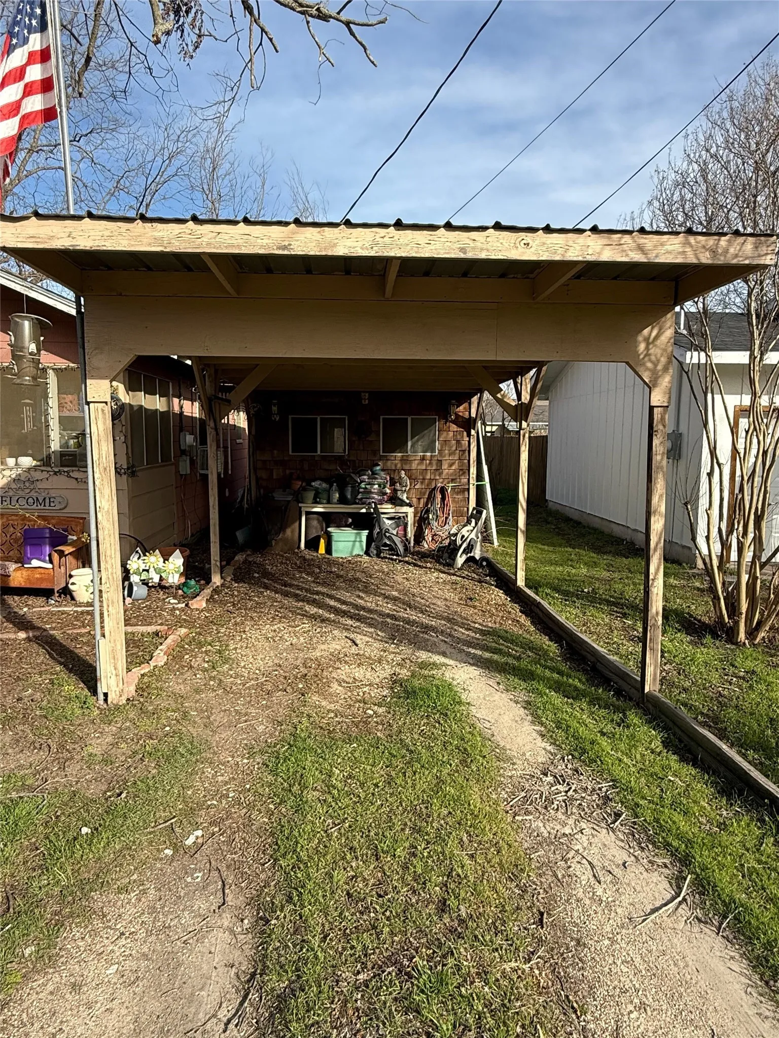 View of parking featuring dirt driveway and a carport