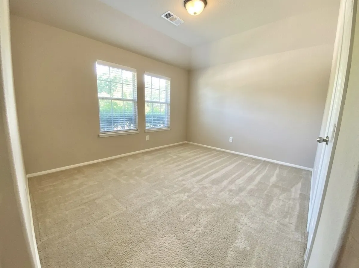 Spare room featuring light carpet and vaulted ceiling