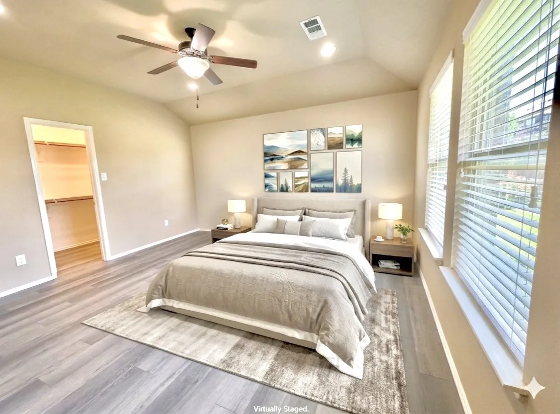 Bedroom featuring wood-like-finish flooring, a vaulted ceiling, and dual windows with blinds. Virtually staged.