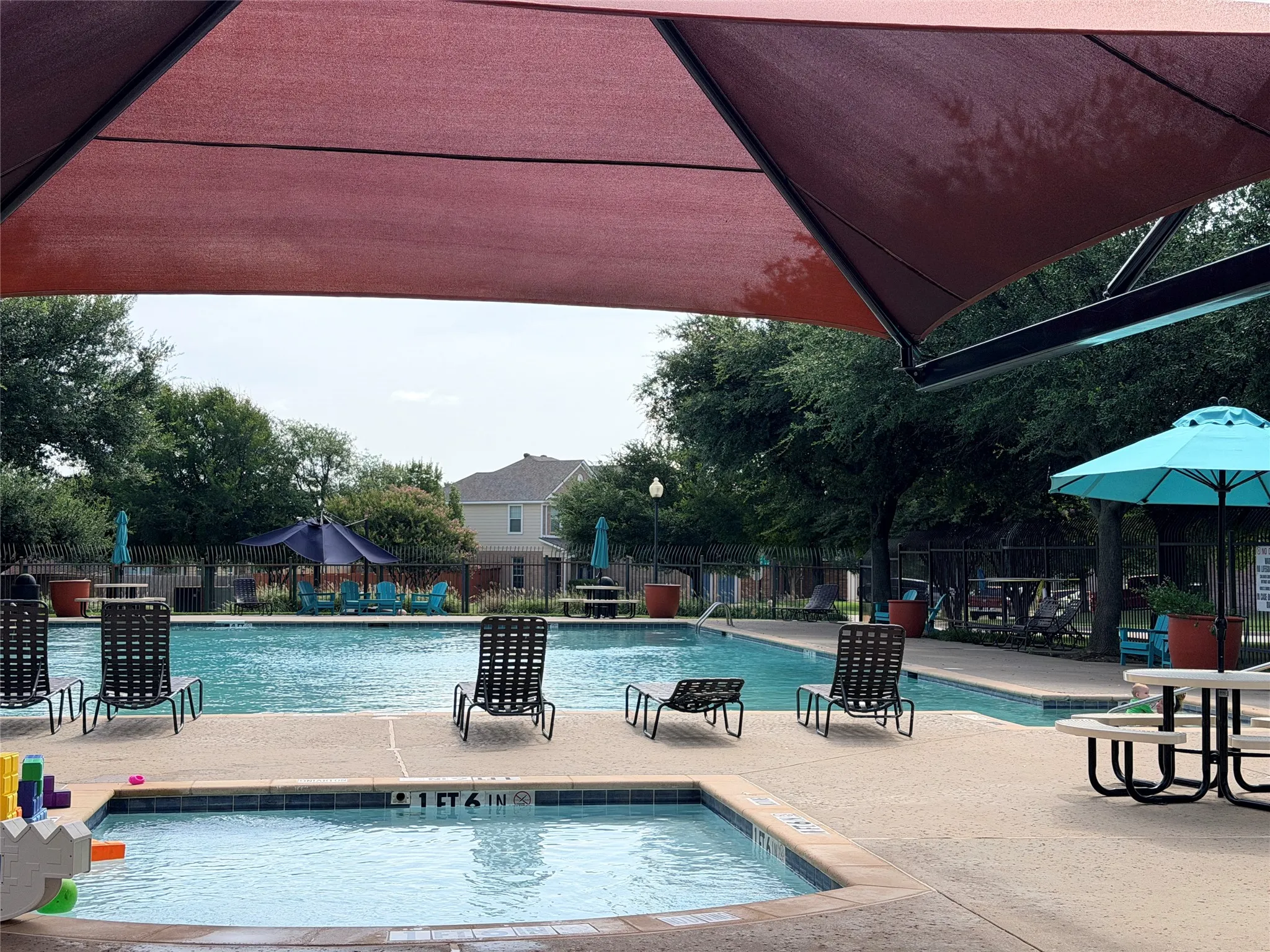 Resort-style pool area featuring multiple swimming pools, a shallow wading area, and a large sunshade structure
