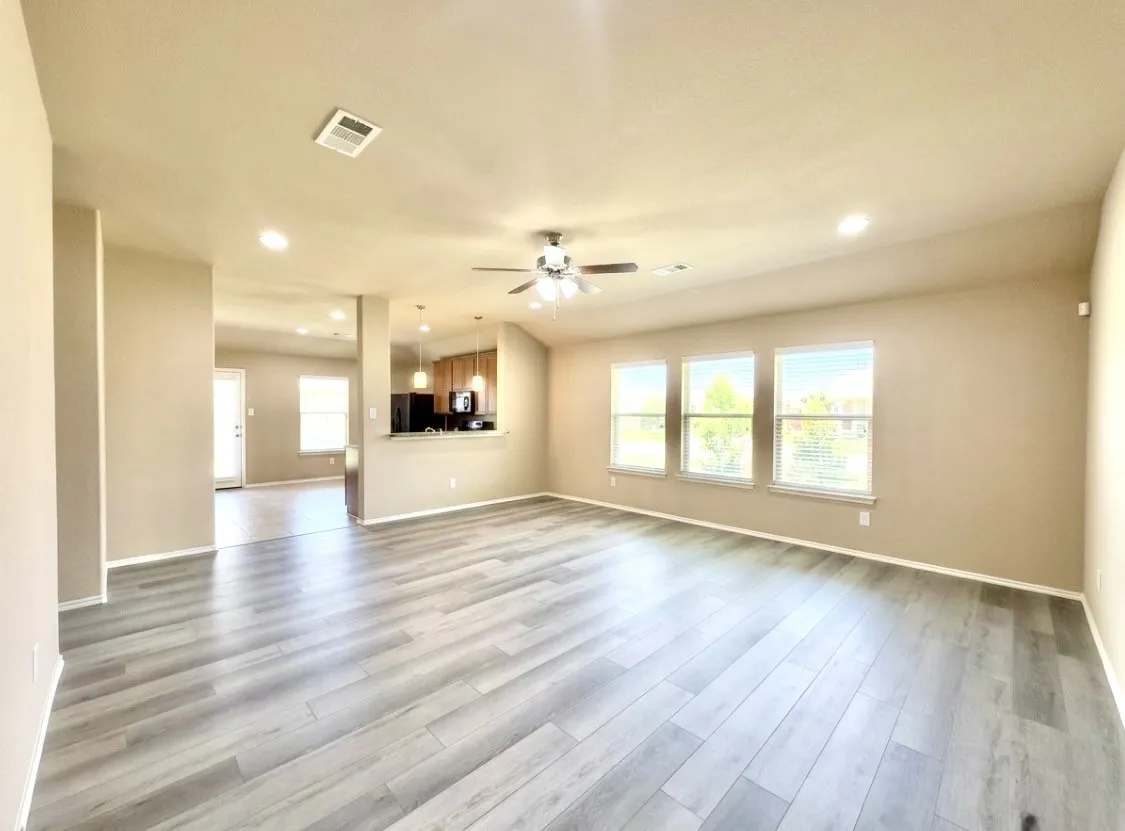 Spacious living area featuring wood-like finish flooring, recessed lighting, and a ceiling fan